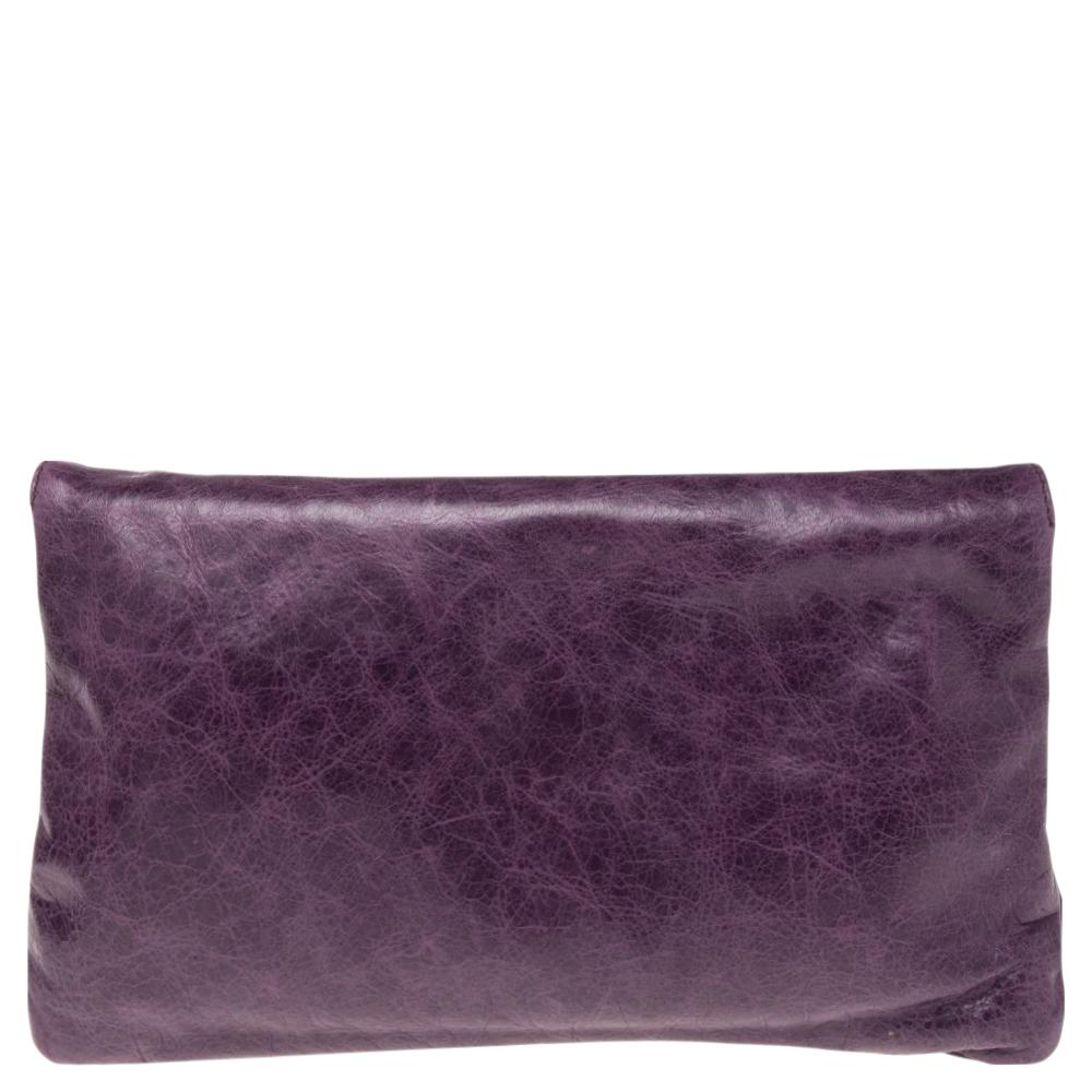 This glimmering purple Balenciaga clutch is ready to carry your girly essentials in a chic manner. This flap-over style clutch is crafted from leather and decorated with large studs, corner buckle detailing, and a front zip pocket. The interior is