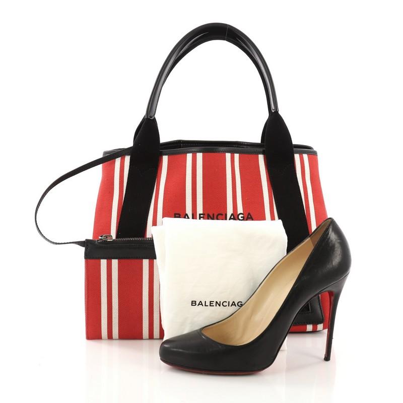 This Balenciaga Navy Cabas Canvas with Leather Small, crafted in red and white striped canvas, features dual leather handles, stamped Balenciaga Paris logo, and silver-tone hardware. It opens to a matching off white canvas interior. **Note: Shoe