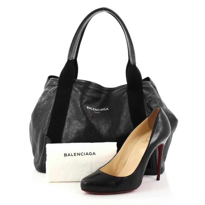 This authentic Balenciaga Navy Cabas Leather Small is your perfect accessory for your everyday looks. Crafted in black leather with black canvas trims, this tote features dual handles, stamped Balenciaga Paris logo, side snap button, and silver-tone