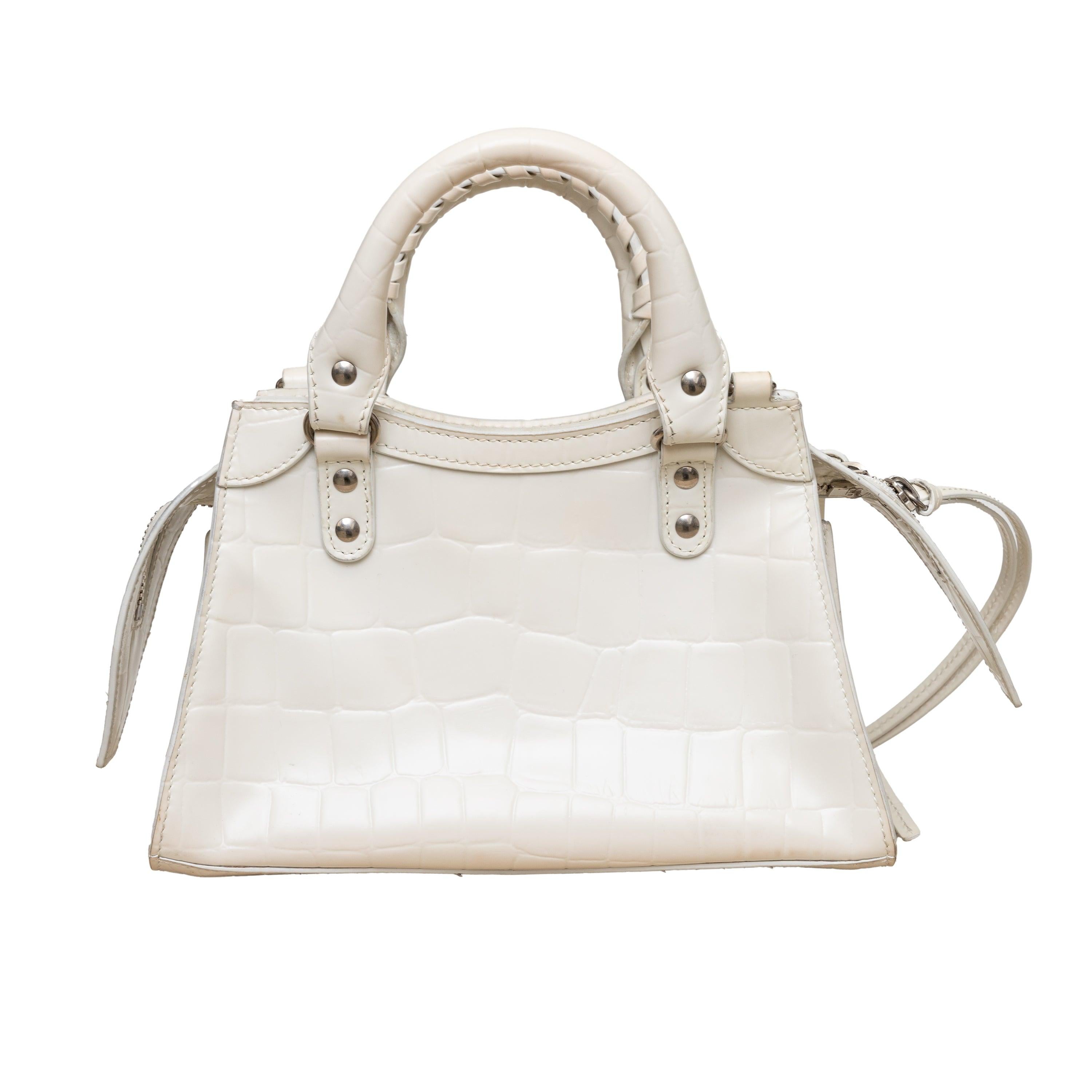 The Balenciaga Neo Classic mini top handle bag remains a classic and crowd favourite! Made in Italy with white leather and embossed crocodile leather effect, this sturdy bag features silver-tone hardware and can be carried by the top handles or worn