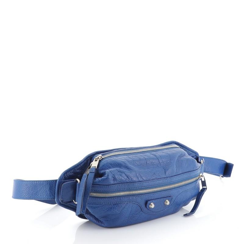 This Balenciaga Neo Lift Classic Studs Waist Bag Leather, crafted in blue leather, features an adjustable waist strap, classic studs detail, front zip pocket and silver-tone hardware. Its top zip closure opens to a black fabric interior. 

Estimated