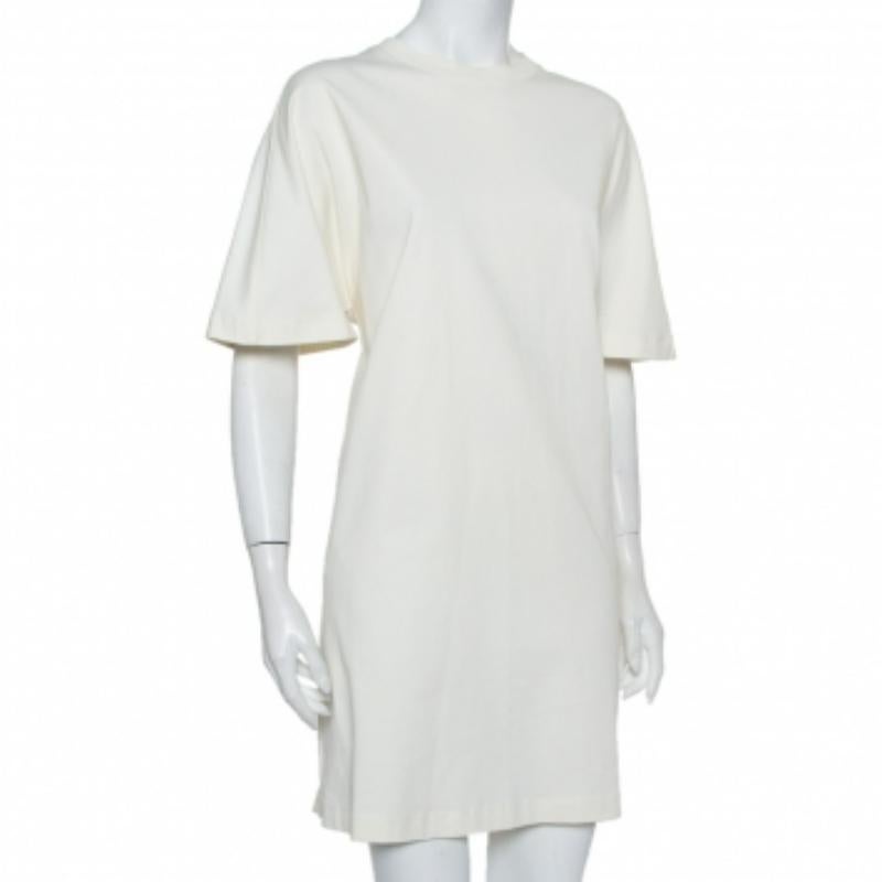 Elegance combined with style, you cannot go wrong with this Balenciaga t-shirt dress. This cream dress is designed in a simple silhouette with a crewneck and short, relaxed sleeves. Trendy, this cotton knit dress will look best with a denim jacket