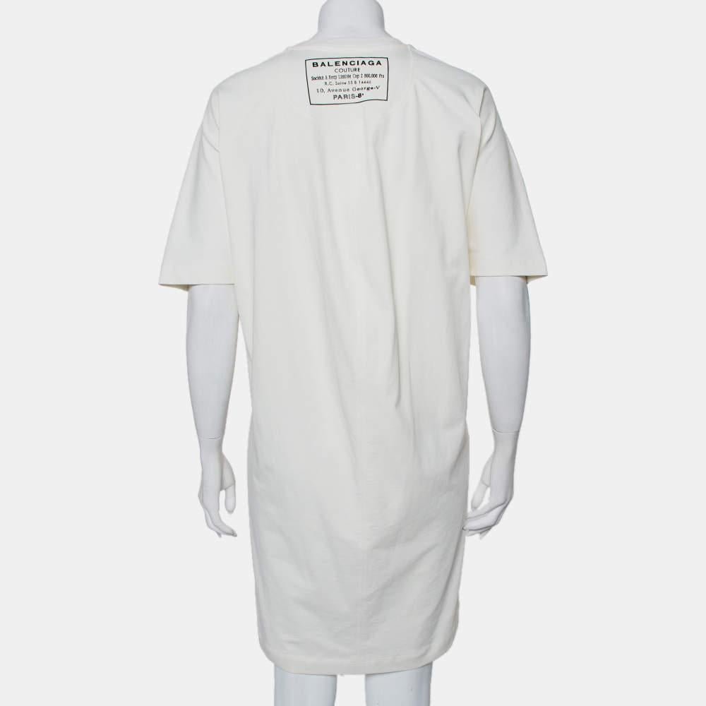 Elegance combined with style, you cannot go wrong with this Balenciaga t-shirt dress. This cream dress is designed in a simple silhouette with a crewneck and short, relaxed sleeves. Trendy, this cotton knit dress will look best with a denim jacket