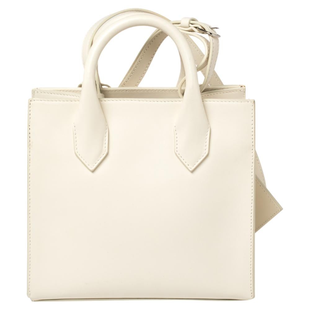 A perfect bag to pair with almost all your outfits, this Balenciaga Mini All Afternoon tote bag is sure to replace your everyday bag. Crafted in leather in an off-white hue, this bag has an elegant appeal with a silver-tone marble detailed logo