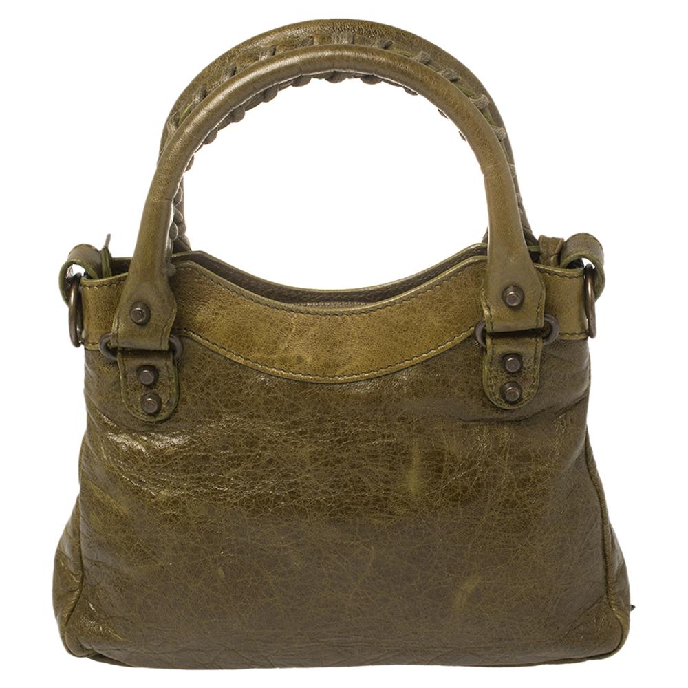 Balenciaga is known for its finely made products and this bag is one of them. Effortless and stylish, this olive leather bag will be your go-to for multiple occasions. It has the signature details of buckles, studs, and the front zipper. Two top