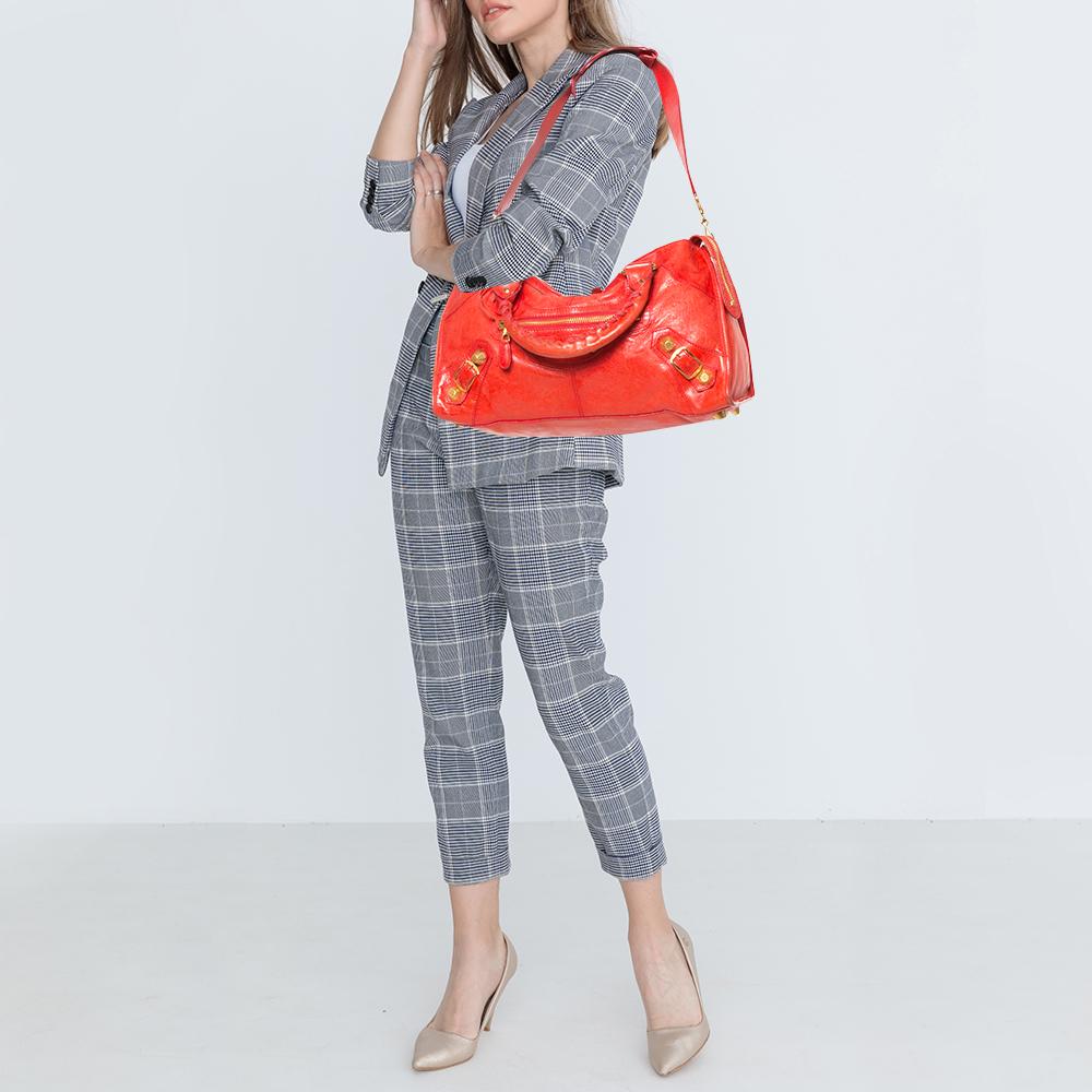 This Part-Time tote from Balenciaga is perfect for all your outings. This leather bag is unique in its silhouette and features an interplay of large studs and buckles. With a creative edge, the bag has a front zip pocket, round leather handles, and