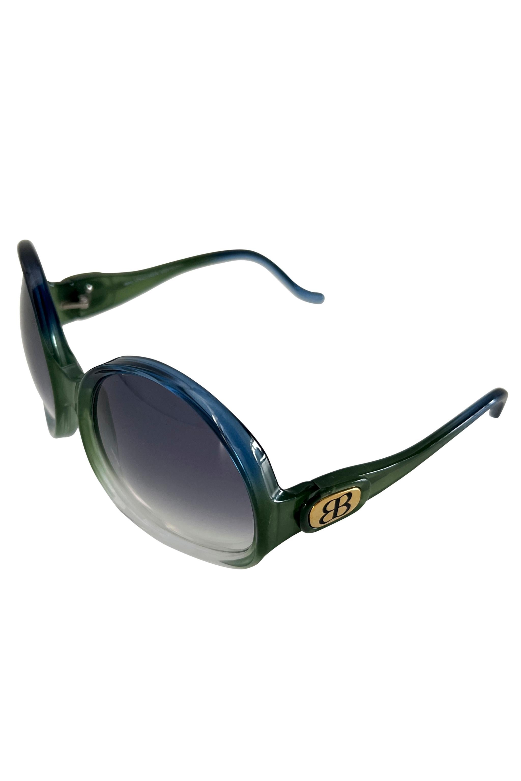 Resurrection Vintage is excited to offer a pair of vintage oversized Balenciaga sunglasses, featuring blue and green acrylic frames, gold 'BB' logos, and grey lenses. Original case included. 
Balenciaga Paris
Size: One Size 
Original Case