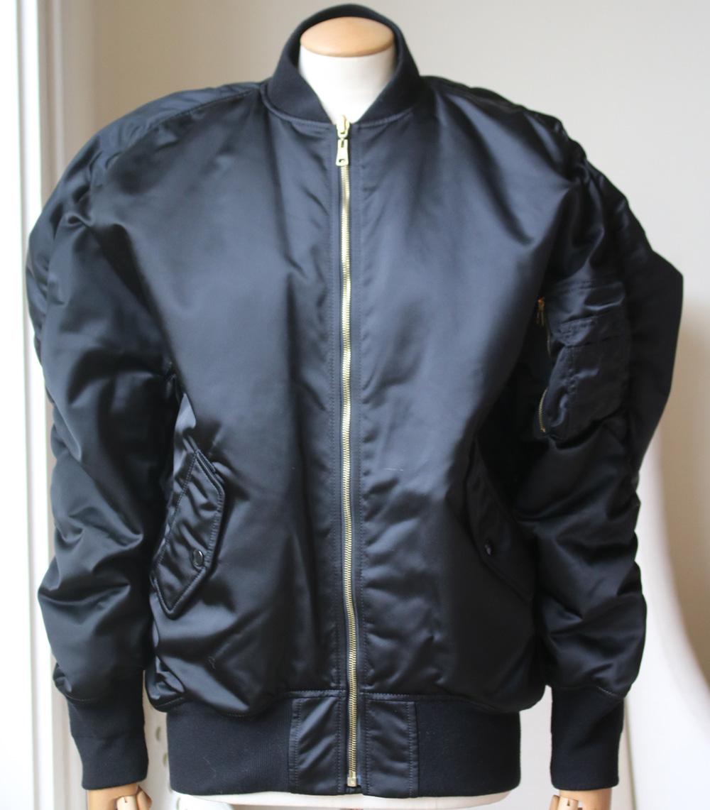 Made in Italy, this piece is generously padded for insulation and has ruched seams that accentuate its oversized, cocoon-like shape. It's finished with ribbed jersey trims and has functional snap-fastening pockets inside and out. Black satin. Zip