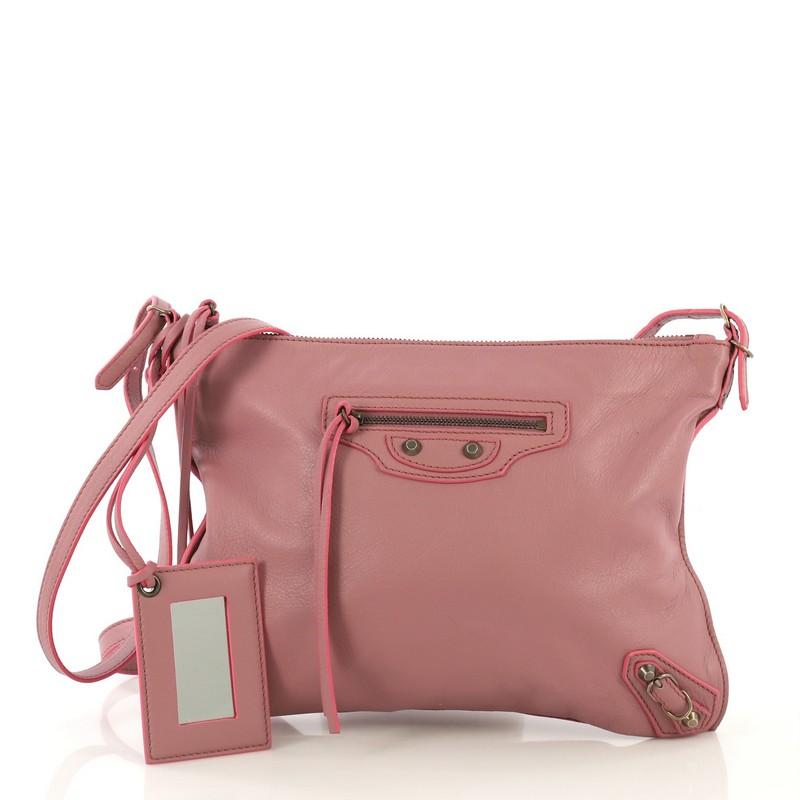 This Balenciaga Papier Neo Crossbody Bag Leather, crafted from pink leather, features a leather cross-body strap, classic hardware studs, front zip pocket, and aged gold-tone hardware. Its top zip closure opens to a pink suede interior with slip