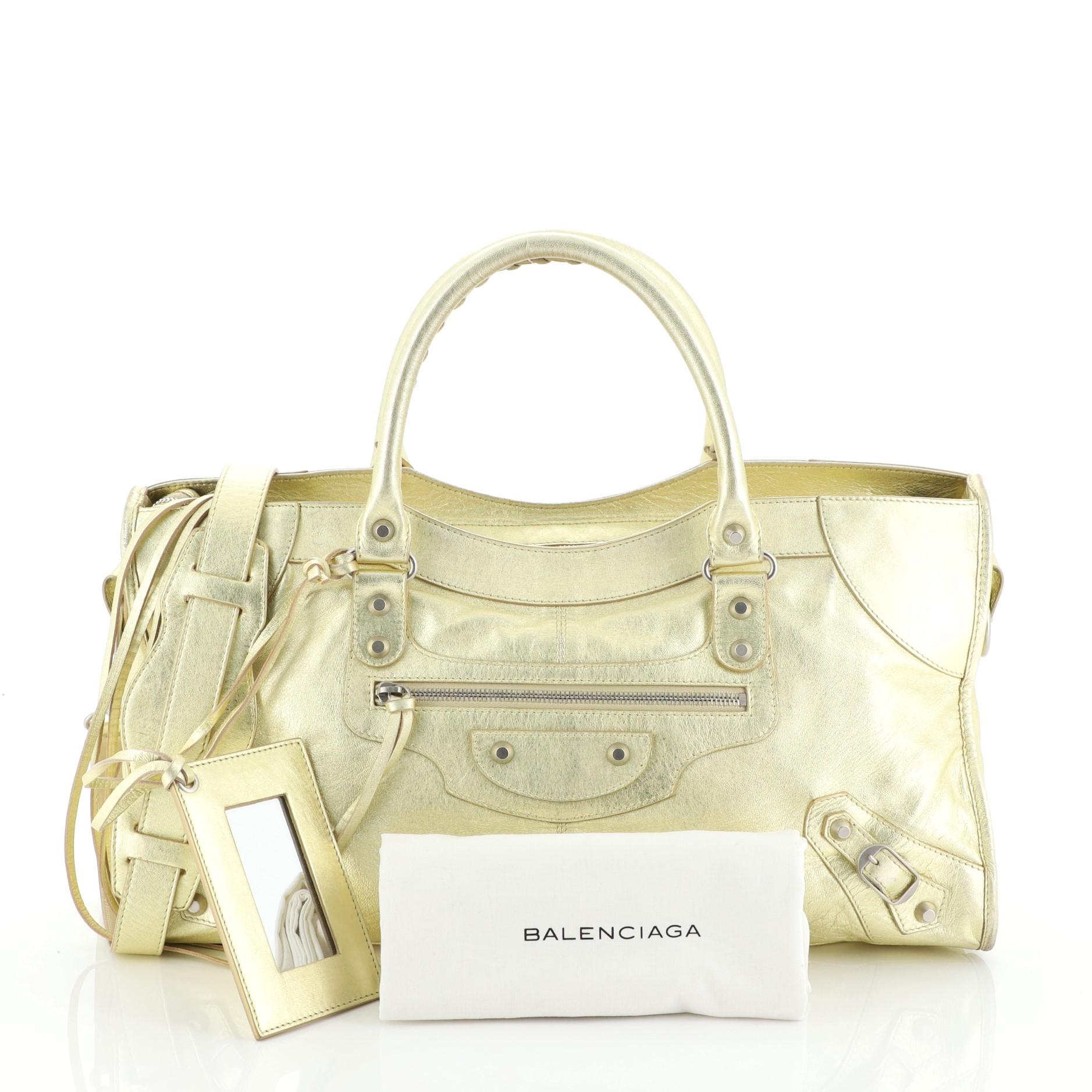 This Balenciaga Part Time Classic Studs Bag Leather, crafted from gold leather, features dual braided woven handles, classic studs and buckle details, front zip pocket, and silver-tone hardware. Its top zip closure opens to a black fabric interior