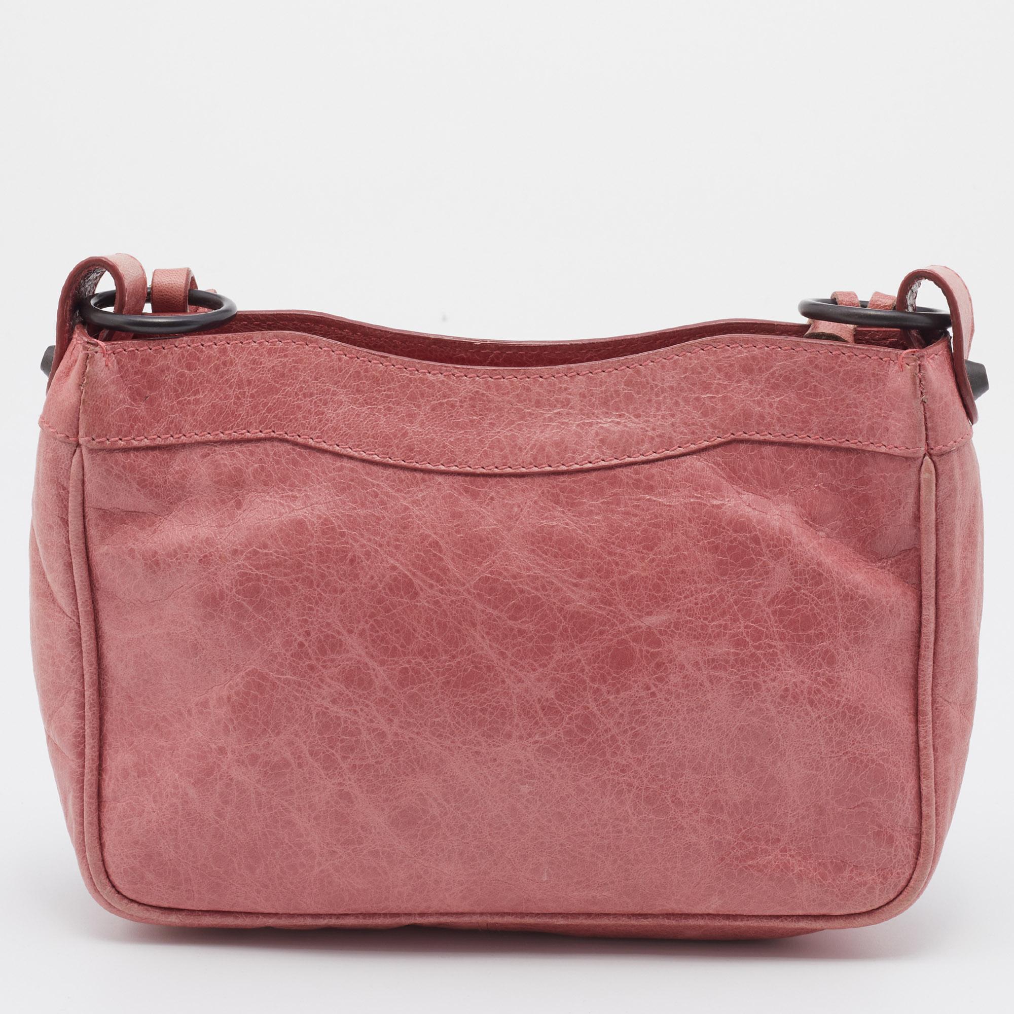 This Balenciaga handbag is an example of the brand's fine designs that are skillfully crafted to project a classic charm. The bag is made of pink leather and added with bronze-tone hardware, a short handle, and a lined interior.

Includes: Mirror
