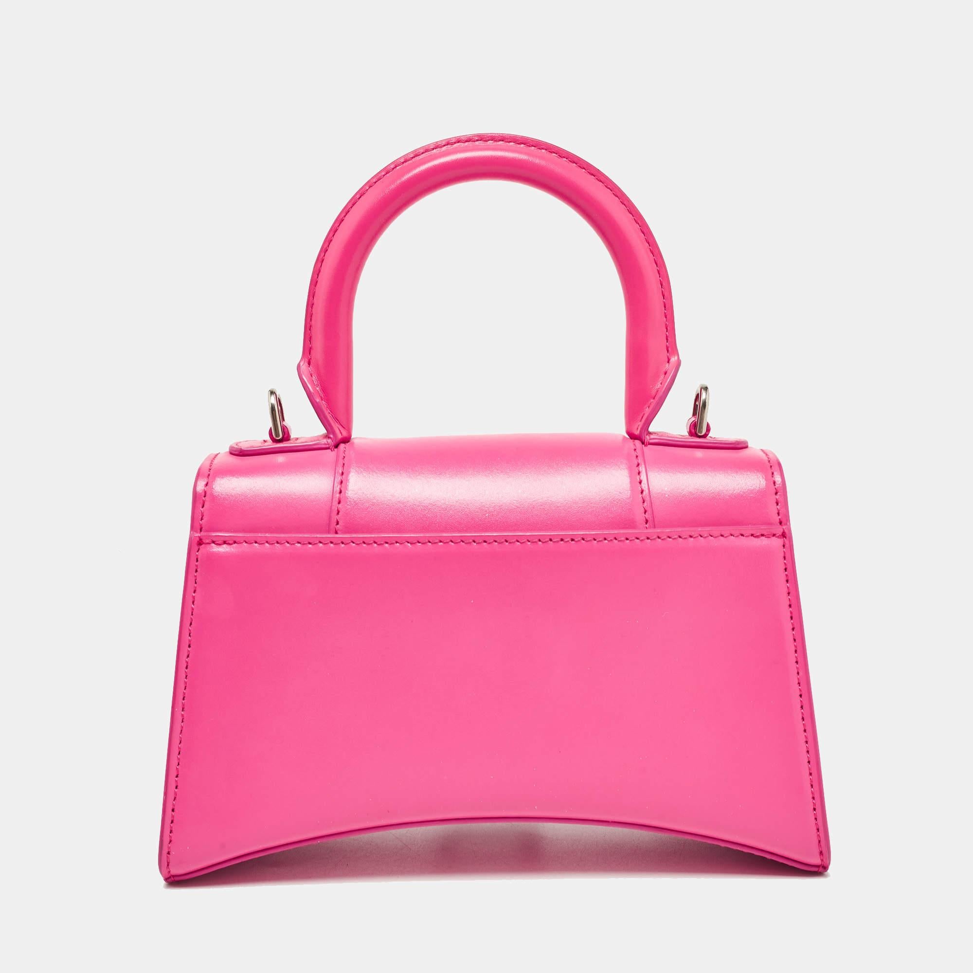 Balenciaga's Hourglass bag is fast becoming a must-have bag. Crafted using leather, the XS Hourglass top handle bag is styled with a flap that has the iconic B logo. The bag has a lined interior, a shapely top handle, and a shoulder