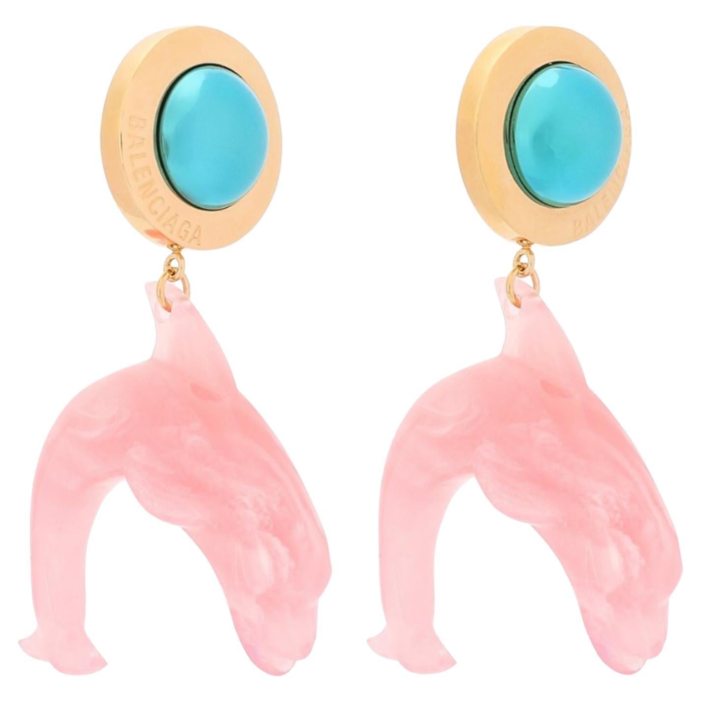 Gold and pink Mermaid Dolphin earrings from Balenciaga featuring a carved resin pendant, engraved logo, blue accent, and a post-stud fastening. 

COLOR: Pink and gold
MATERIAL: 100% brass, 100% resin, 100%
ITEM CODE: 619911
MEASURES: H 2.25” x L