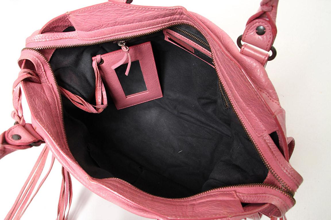 The Pink Balenciaga Motocross Classic City features a lambskin leather, stud details, an exterior zip pocket, rolled whipstitched handles, a detachable shoulder strap, a top zip closure, canvas lining, and an interior zip pocket. 

Strap drop 25 cm. 