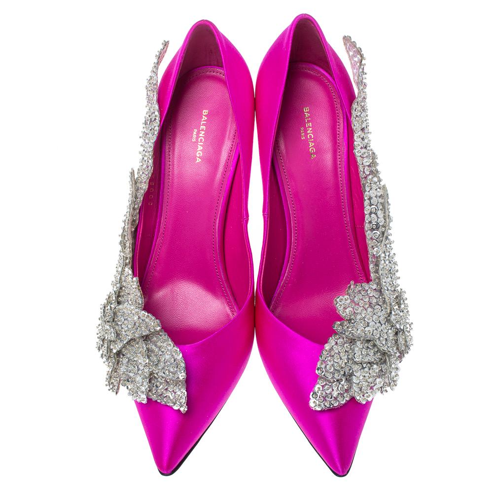 Exquisite crystal-embellished appliques wreathe these gorgeous pumps from Balenciaga! Pretty in pink, they have been crafted from rich satin into a pointed toe silhouette and will lift you up most elegantly with their stiletto heels. Endowed with