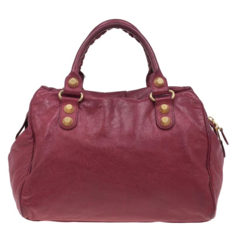 This Balenciaga Red Giant Velo Satchel is practical and stylish. Made from fine lambskin, it features a front zipper pocket, stud motifs and protective feet in gold-tone hardware and rolled handles with stitch designs. This bag is lined with black