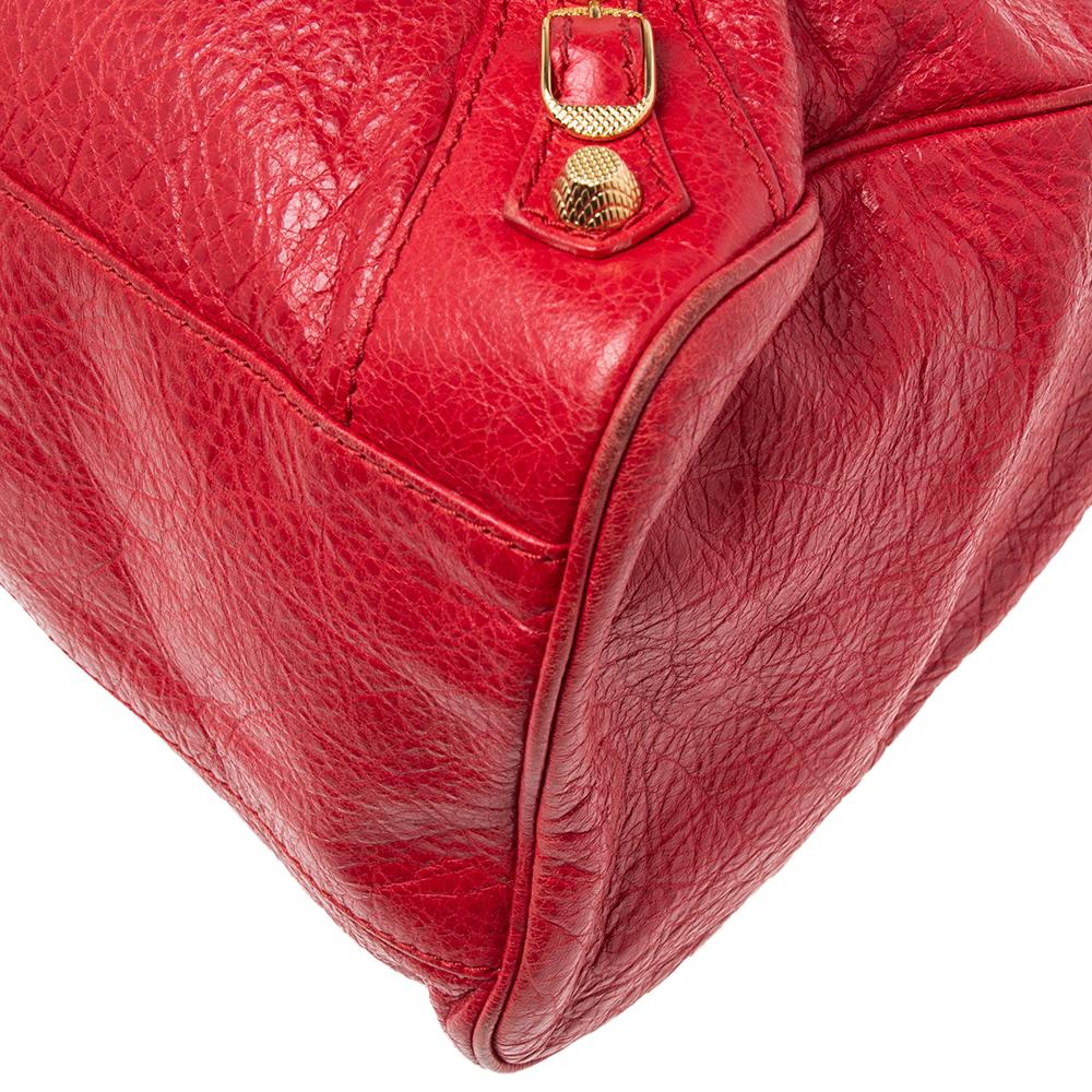 This GGH Motorcycle First bag from the House of Balenciaga is very chic and elegant in appearance and style. It has been created using red leather on the exterior, granting it a chic-feminine design. This bag shows dual handles and gold-toned