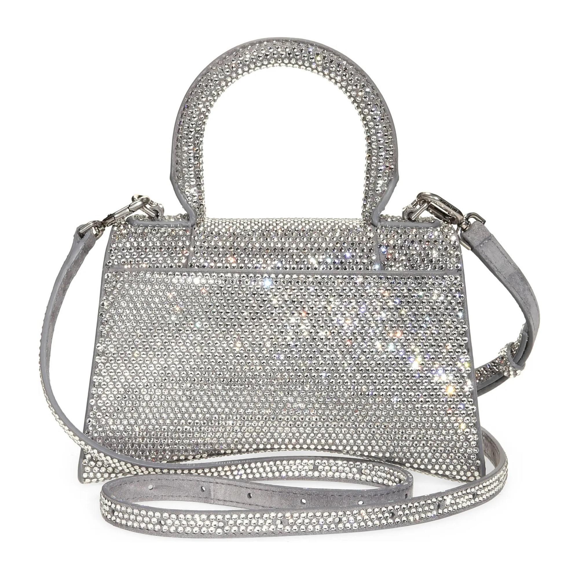 First launched in 2019, the Hourglass bag has become an iconic Balenciaga hallmark. This rendition is constructed of smooth leather embellished with rows of shimmering crystals in silver. The bag features the classic B-shaped logo charm at the