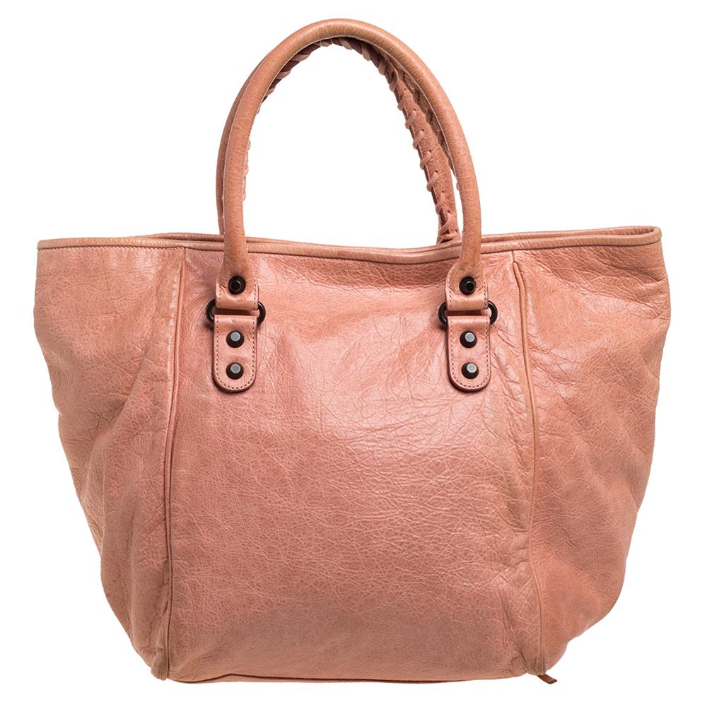 An elegant addition for your tote collection, this Sunday tote bag from Balenciaga has an attractive exterior and slouchy body that exude a bold style. Crafted from peach-hued leather, the bag features dual top handles and bronze-tone hardware.