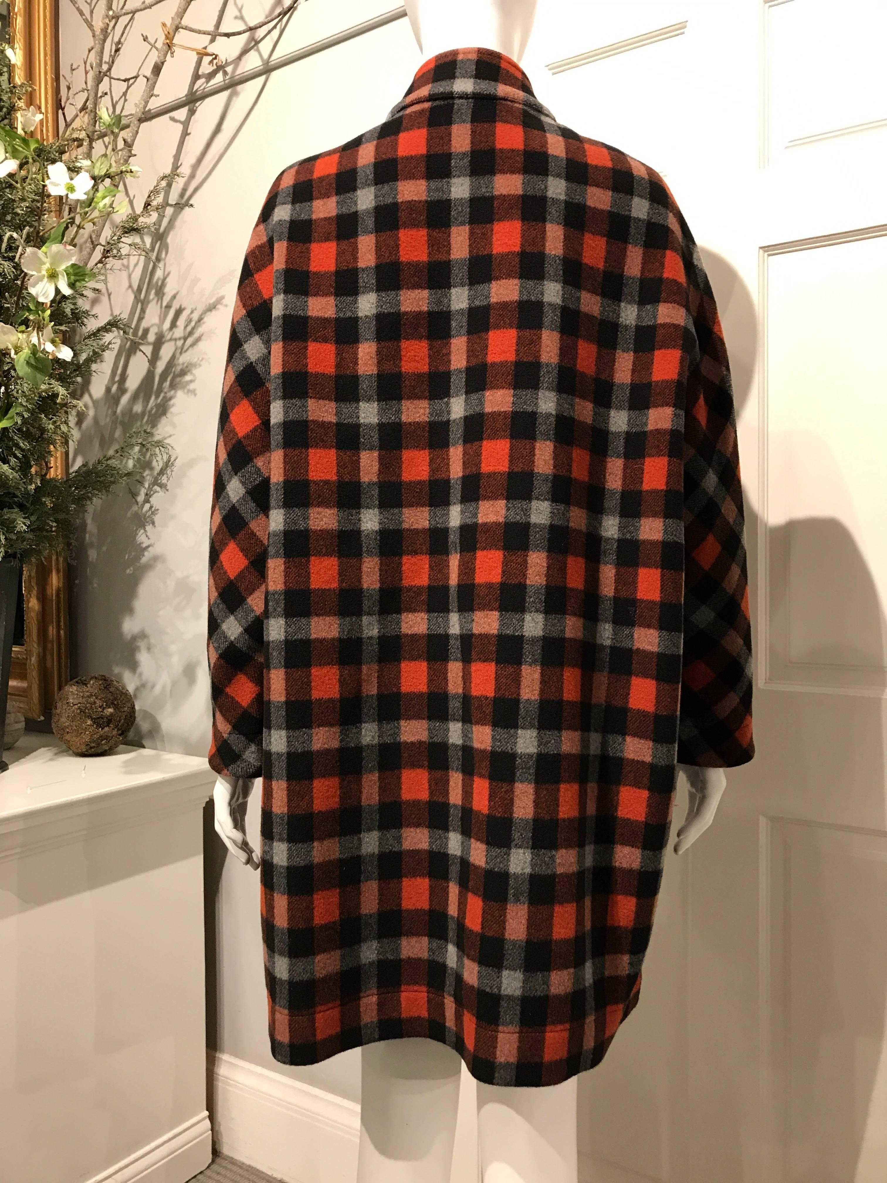Balenciaga coat in a rust-red, black and grey checkered double sided wool fabric dark brown on the inside. The coat closes with pewter colored snaps. It has two big top pockets with flaps on the front and a small breast pocked on the inside in