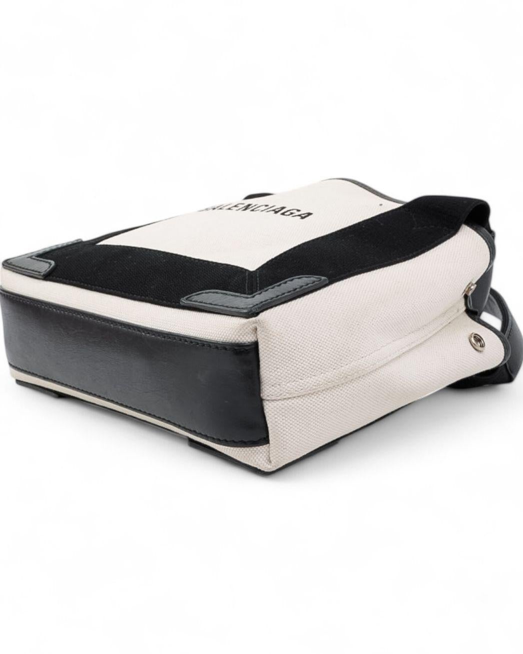 Borsa Balenciaga modello Shopping Small, realizzata in canvas beige e nero con rifiniture in pelle e hardware argentato. Non dotata di chiusura, presenta un interno rivestito in tessuto nero, ampio e capiente. La borsa è munita di doppio manico per