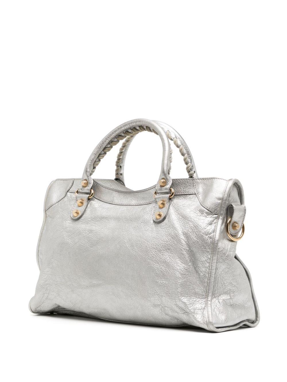 * Silver-tone wrinkled calf leather
* Gold-tone stud detailing
* Decorative buckle detailing
* Leather mirror tag
* Two rolled top handles
* Detachable shoulder strap
* Top zip fastening
* Front zip-fastening pocket
* Internal zip-fastening pocket
*