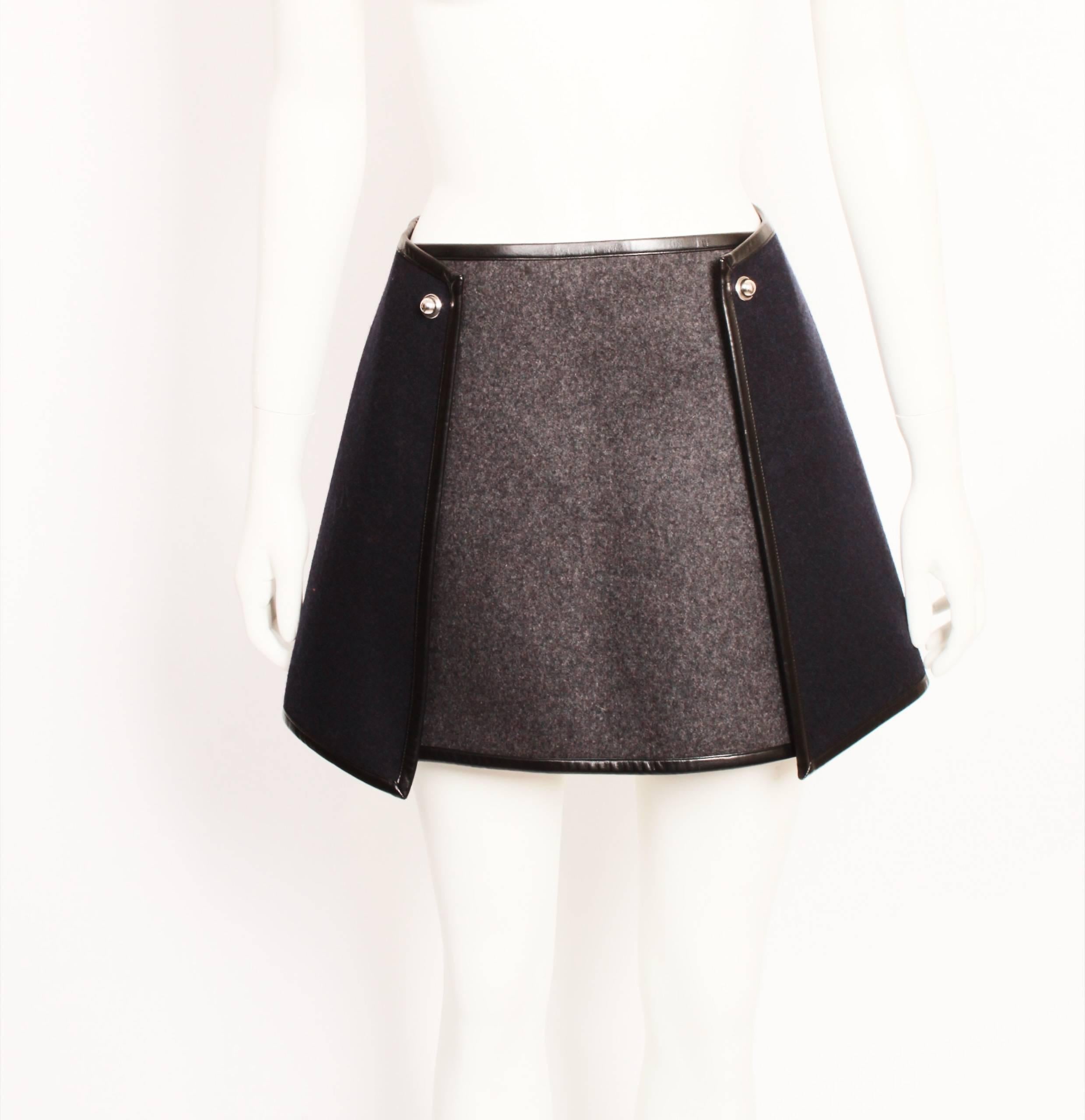 From the Luxury fashion house Balenciaga known for its mini skirts with feminine yet ultra-modern shapes comes this navy & charcoal stiff Wool Mini with silver hardware and hidden press studs on left hand side. 