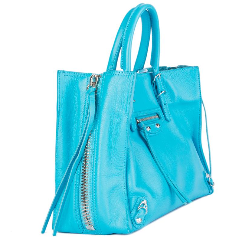 100% authentic Balenciaga 'Papier A6 Side Zip Tote' shoulder bag in sky blue smooth calfskin. Features zip side gussets and polished silvertone hardware. Tassel-trimmed zip pocket and metal buckles and studs at front. Opens with a magnetic button on