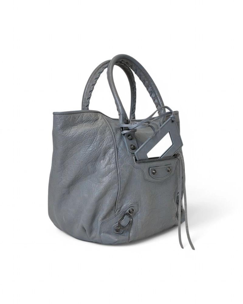 Sac Sunday City de Balenciaga en taille MM, en cuir mordoré bleu clair et cuir dur bronze. Doté d'une fermeture magnétique interne, d'une doublure intérieure en tissu noir et d'une pochette pratique, le sac est très spacieux. Équipé d'une double
