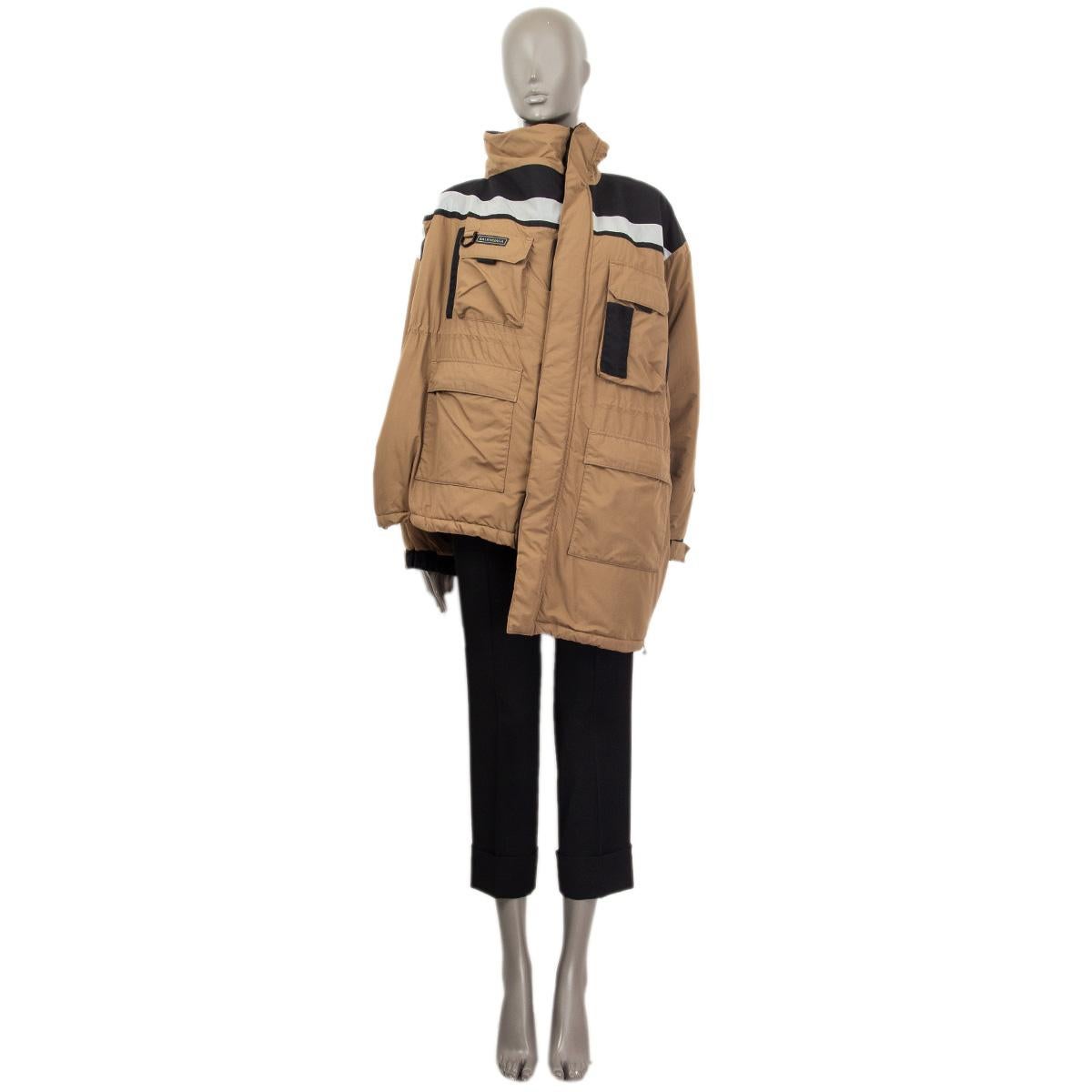 100% authentic Balenciaga asymmetric constructor style jacket in dark tan, black and silver nylone (100%) with a reflecting light strip. Has a stand-up collar, oversize fit and four patch pockets. Cuffs can be adjusted with Velcro fastener. Lined in