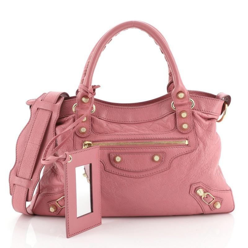 This Balenciaga Town Classic Studs Bag Leather, crafted in pink leather, features braided woven handles, front zip pocket, buckle and studs details, and gold-tone hardware. Its top zip closure opens to a black fabric interior with side zip and slip