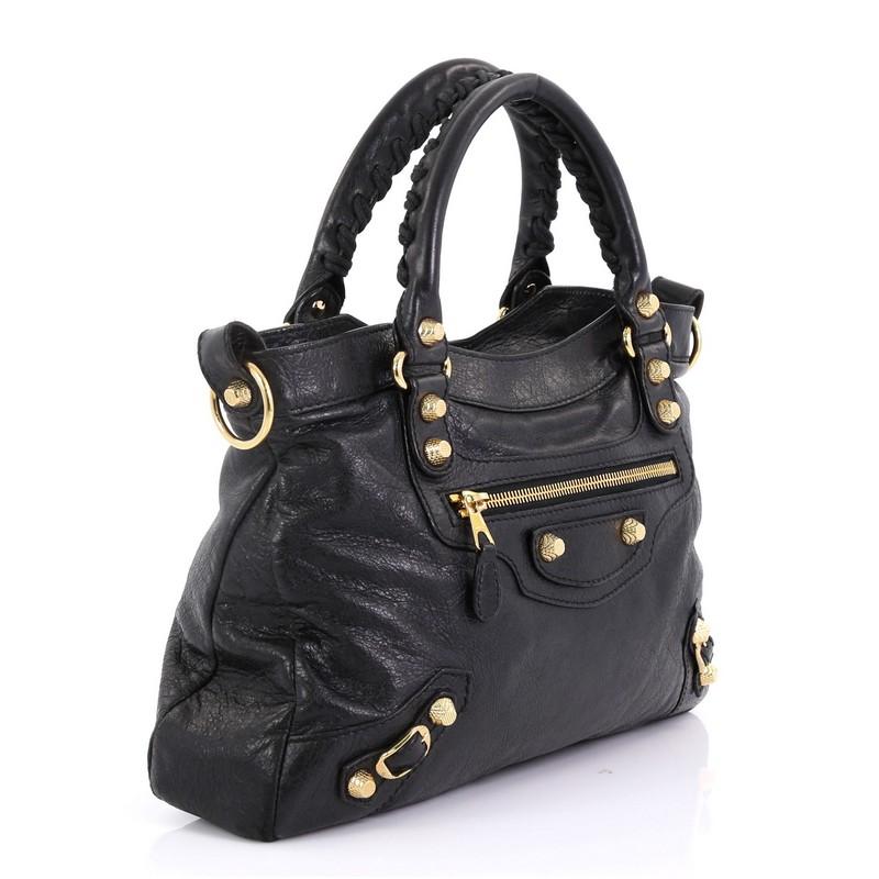 This Balenciaga Town Giant Studs Bag Leather, crafted in black leather, features braided woven handles, front zip pocket, buckle and giant studs details, and gold-tone hardware. Its top zip closure opens to a black fabric interior with zip and slip