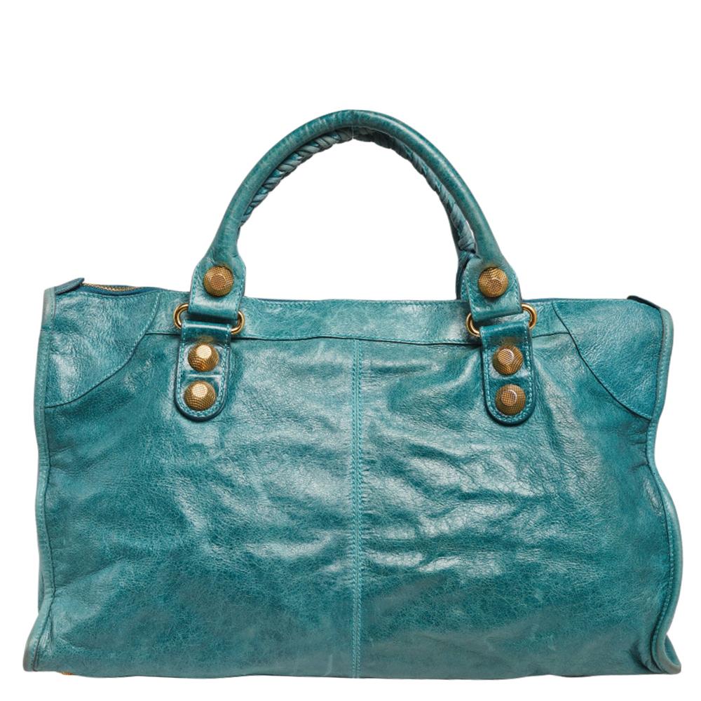 For daily usage, this Balenciaga Work tote is ideal. Crafted from quality leather in a blue shade, the bag has a feminine silhouette with two top handles and gold-tone hardware. The zipper closure opens to a fabric-lined interior and the bag is