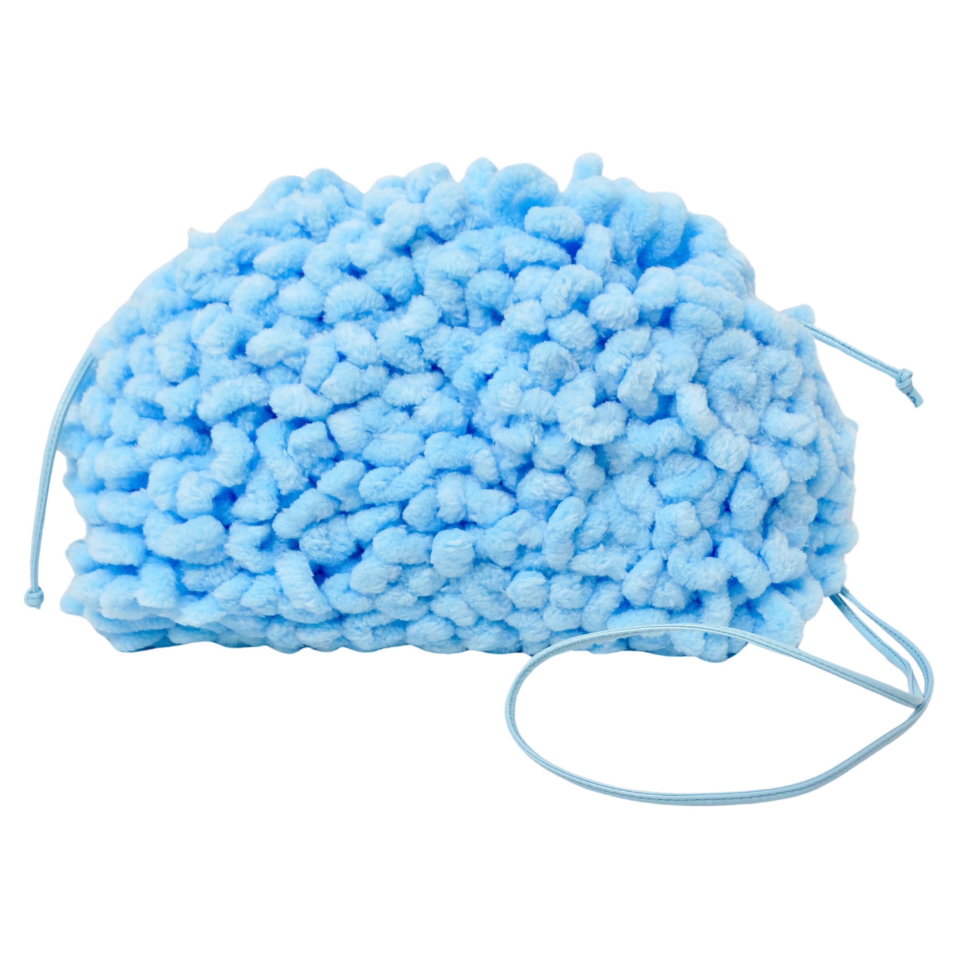 The Balenciaga Veneta Chenille Mini Wave Sky Blue Pouch Clutch is a stunning accessory that exudes both elegance and playful charm. Its exterior features a soft, cloud-like chenille fabric in a delicate sky blue hue, reminiscent of gentle, airy