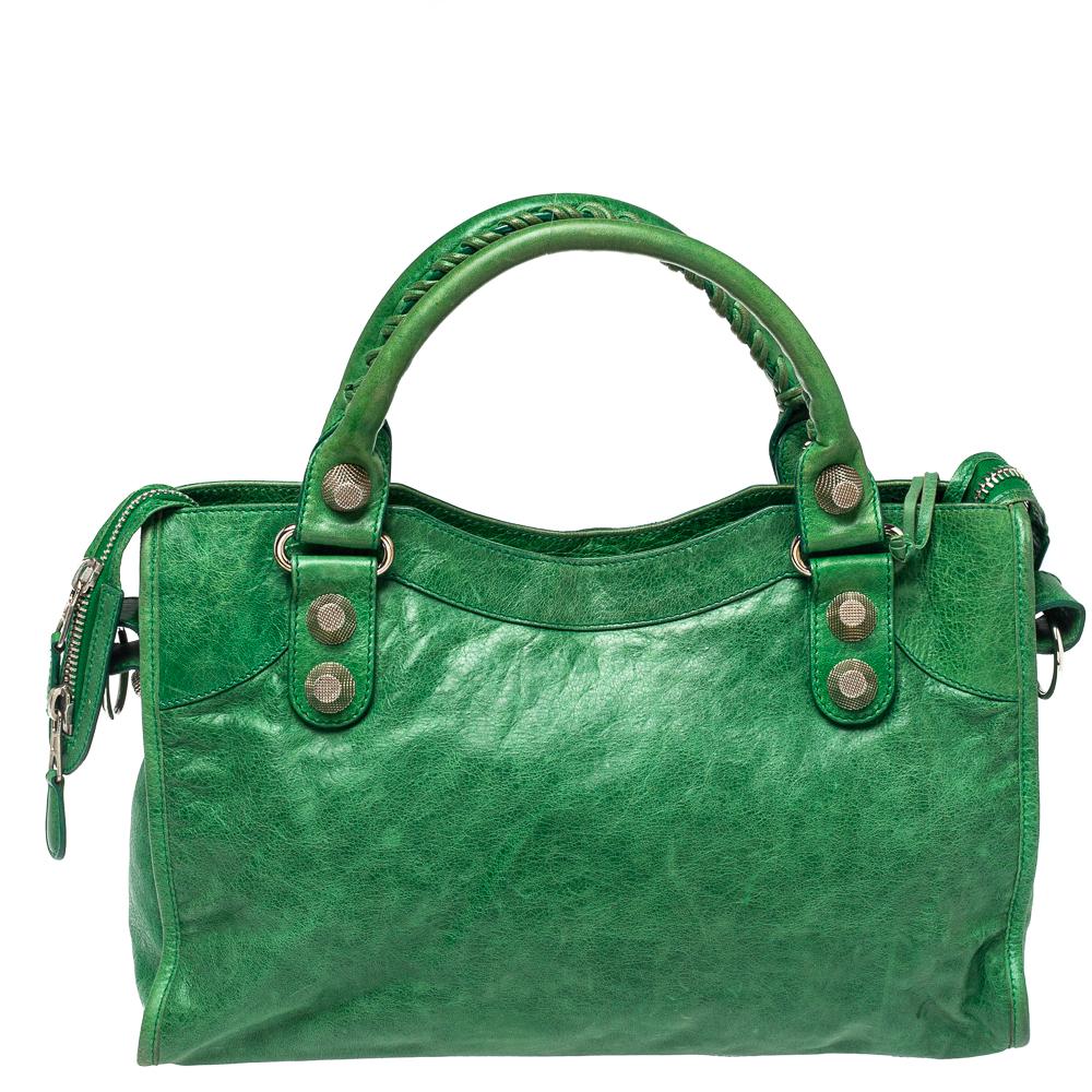A popular bag among celebrities, this SGH city tote by Balenciaga will never leave you unnoticed! It is crafted from Vert Gazon leather and is accented with signature metal buckle and stud details on the front. It comes with an exterior zip pocket