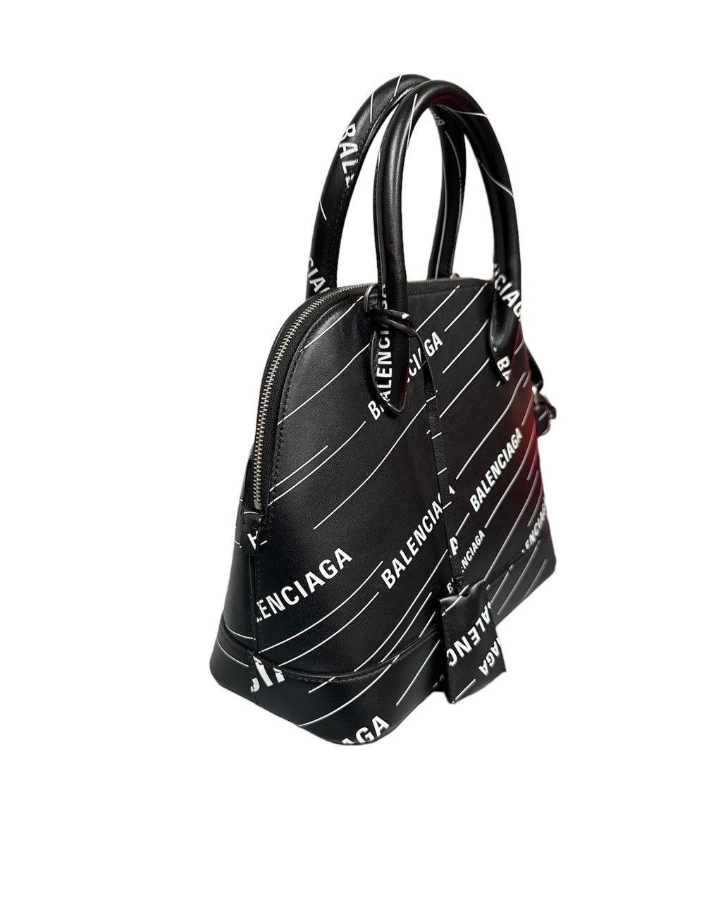 Balenciaga bag, Ville logo print model, made of black leather, white printed logo and silver hardware. Equipped with a double rigid handle in leather and a removable and adjustable shoulder strap to wear the bag by hand and on the shoulder.