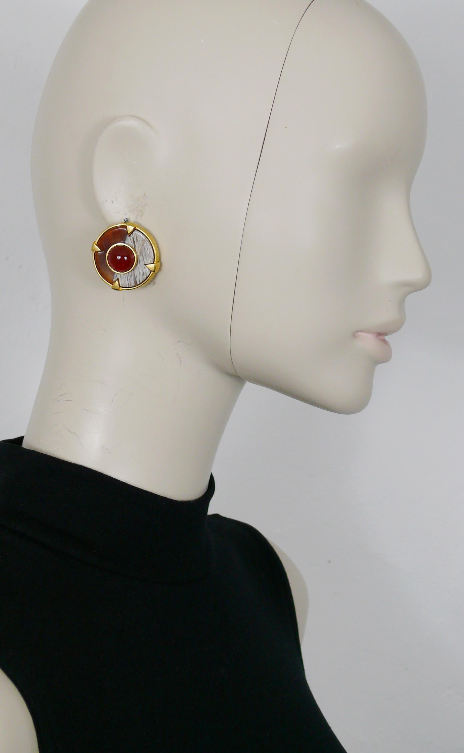 Orecchini a clip a disco in oro vintage di BALENCIAGA con intarsio di resina in finto legno e cabochon in vetro rosso rubino al centro.

BALENCIAGA Paris Made in France in rilievo.

Misure indicative: diametro di circa 3 cm (1,18 pollici).

NOTE
-