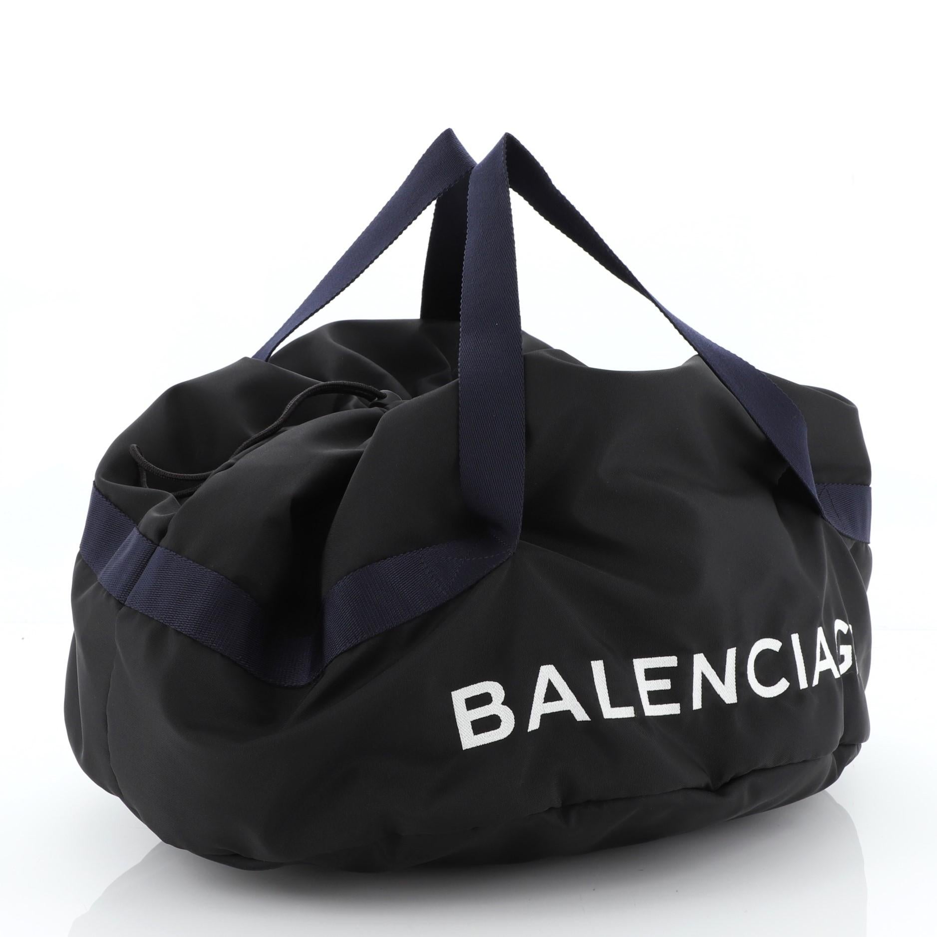 This Balenciaga Wheel Duffle Bag Nylon Small, crafted in black nylon, features dual handles, printed Balenciaga lettering at front and black-tone hardware. It opens to a black nylon interior.

Estimated Retail Price: $1,185
Condition: Excellent.