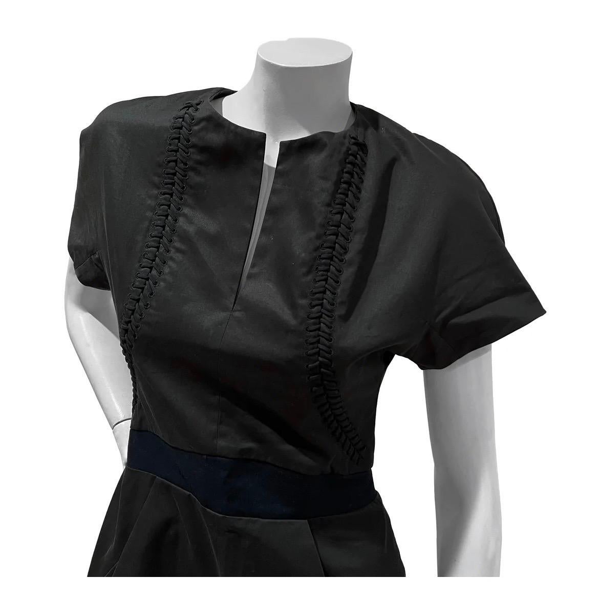 Whipstitch Detail Romper by Balenciaga 
Circa 2007
Made in Italy
Slate gray 
Short sleeves
Center collar slit
Whipstitch detail to waist
Navy blue waist band
Dual front pockets
Dual faux back pockets 
Back zip closure
Fold over cuff hem  
Fabric