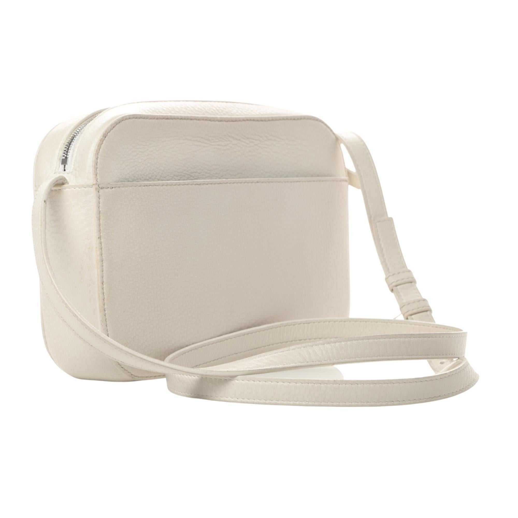 Diese Umhängetasche ist aus weichem Kalbsleder in Weiß gefertigt. Die Handtasche hat eine aufgesetzte Tasche auf der Rückseite, ein weißes Balenciaga-Logo und einen schmalen, verstellbaren Lederriemen. Die Tasche ist innen mit schwarzem Leder