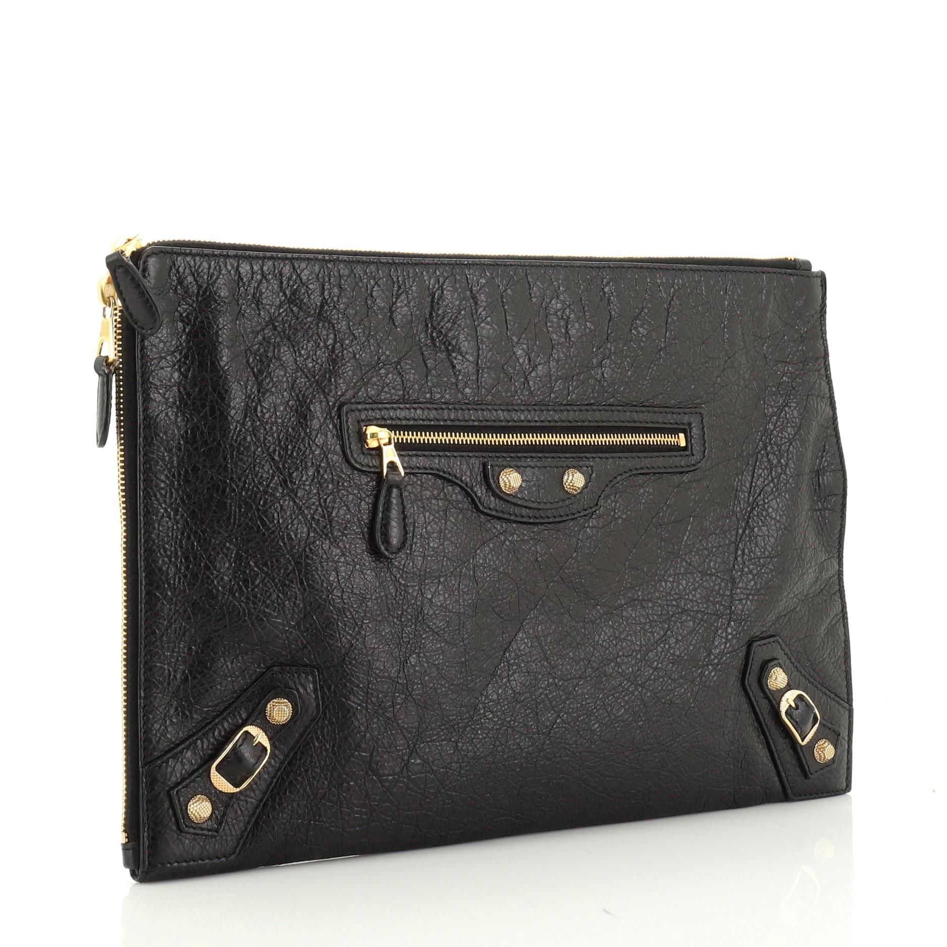 This Balenciaga Zip Around Giant Studs Clutch Leather Medium, crafted from black leather, features studs and buckle details, exterior zip pocket, and gold-tone hardware. Its all-around zip closure opens to a black fabric interior with slip pocket.