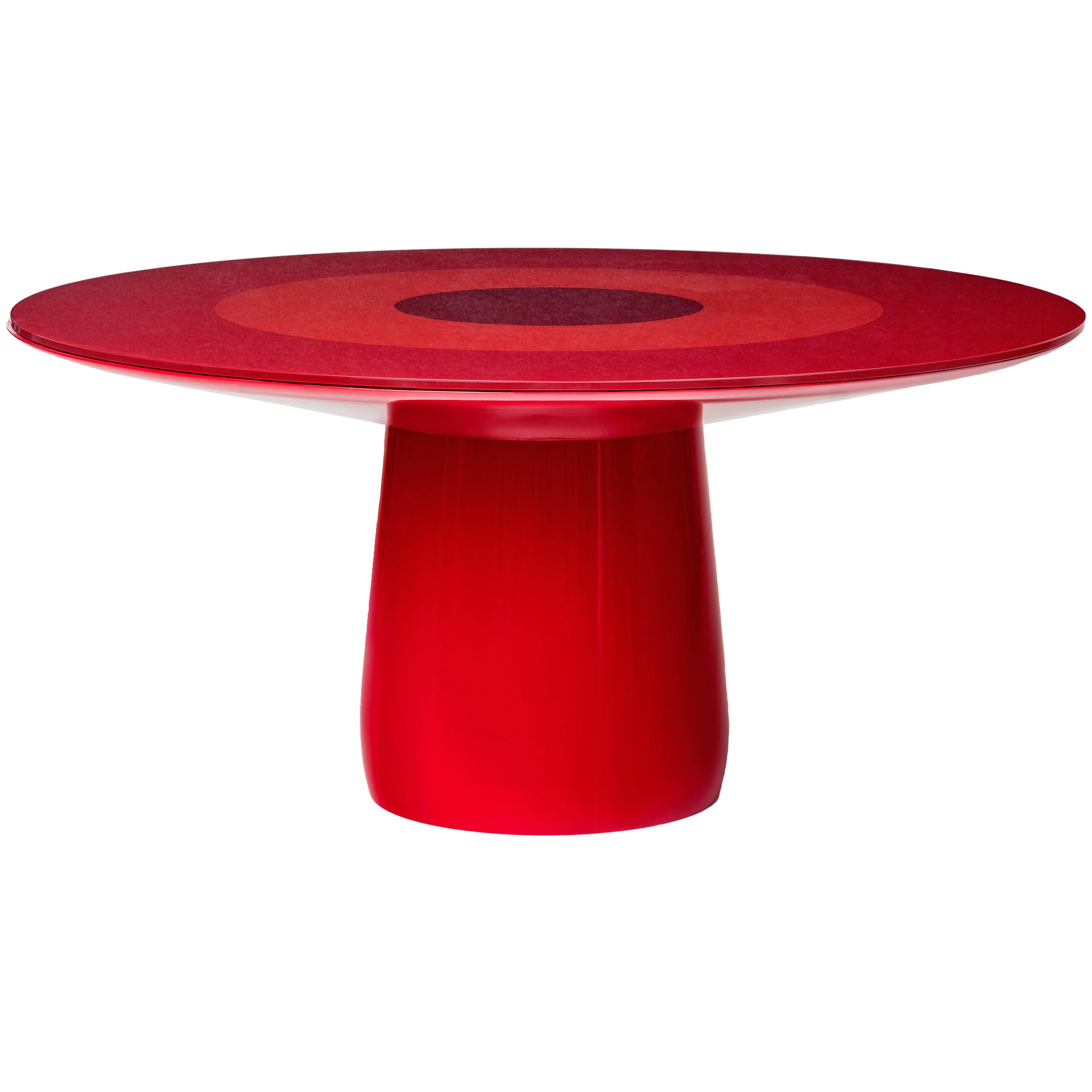 A round table with a central leg and under-surface section made of rigid polyurethane with a soft-polished red lacquered finish. The tabletop made of extra clear tempered glass with concentric red circles painted on the underside.

 