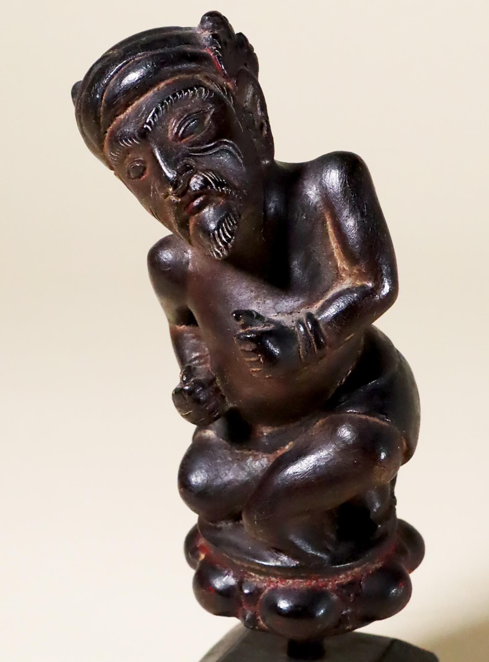 Unique and unusual Balinese ceremonial dagger (kris or Keris) handle depicting a bearded male dwarf. Wood with remains of red paint, 20th century. He wears a sarong and traditional headdress with a flower at the back.
Measures: 5 x 2 x 2 1/2 inches.