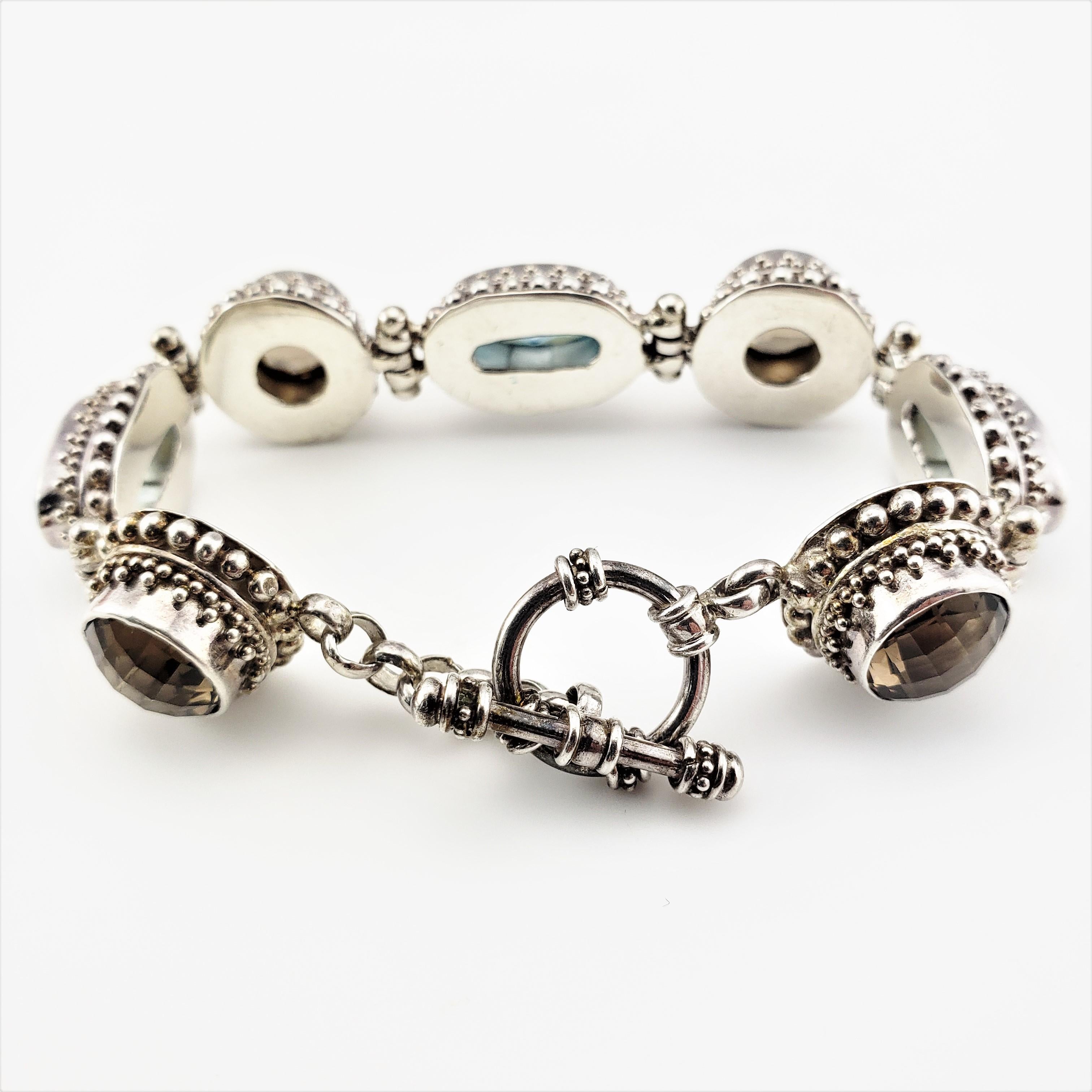 Vintage Bali Indonesia Sterling Silver Blue and Brown Topaz Flexible Toggle Bracelet-

This lovely toggle bracelet features three oval blue topaz gemstones (14 mm x 7 mm each) and three round brown topaz gemstones
(9 mm each) set in beautifully