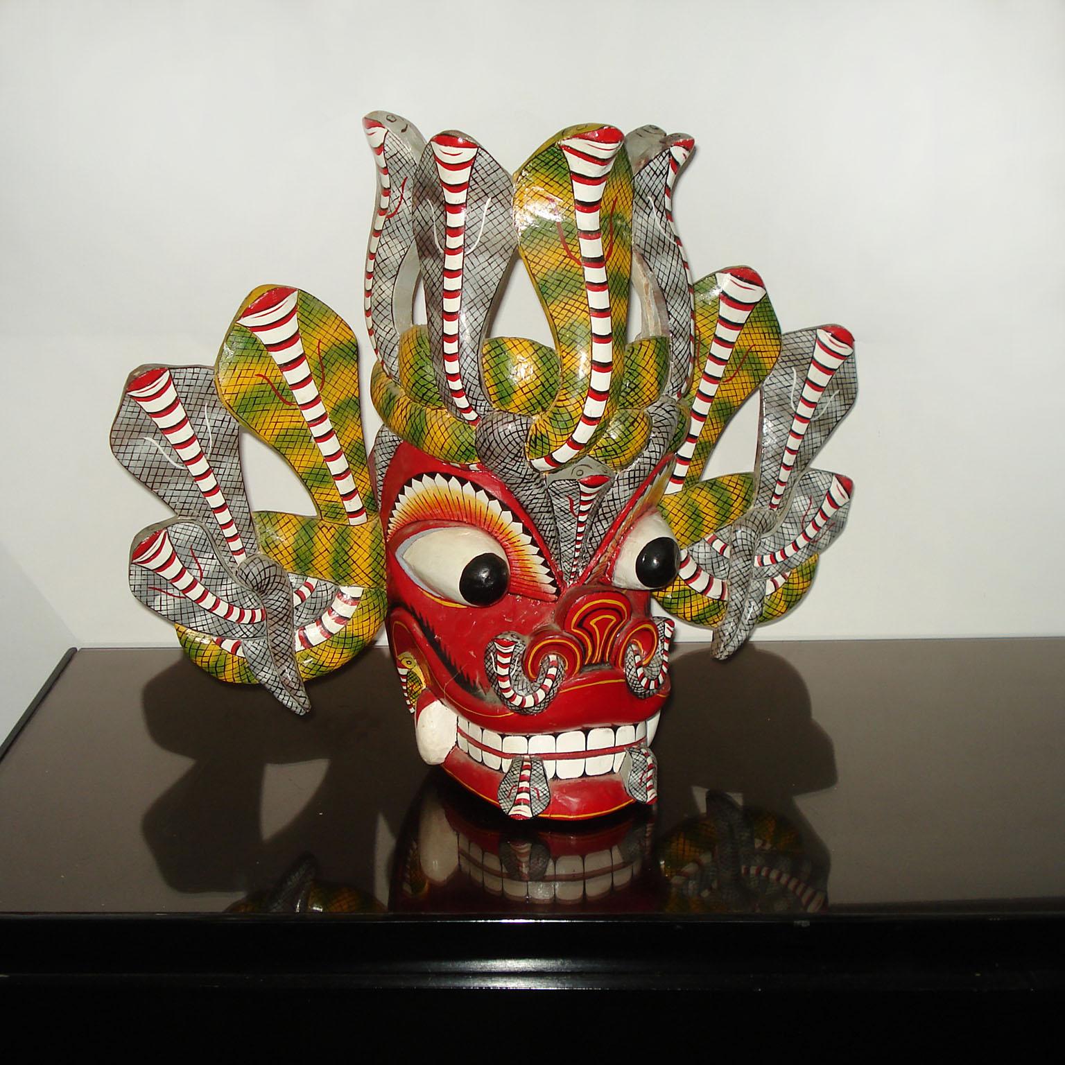 Grand masque de danse balinais Barong en bois sculpté et peint à la main représentant une créature mythologique colorée et ornée.
Habilement sculpté à la main, avec de grands yeux globuleux, de grandes dents et deux serpents dépassant de chaque