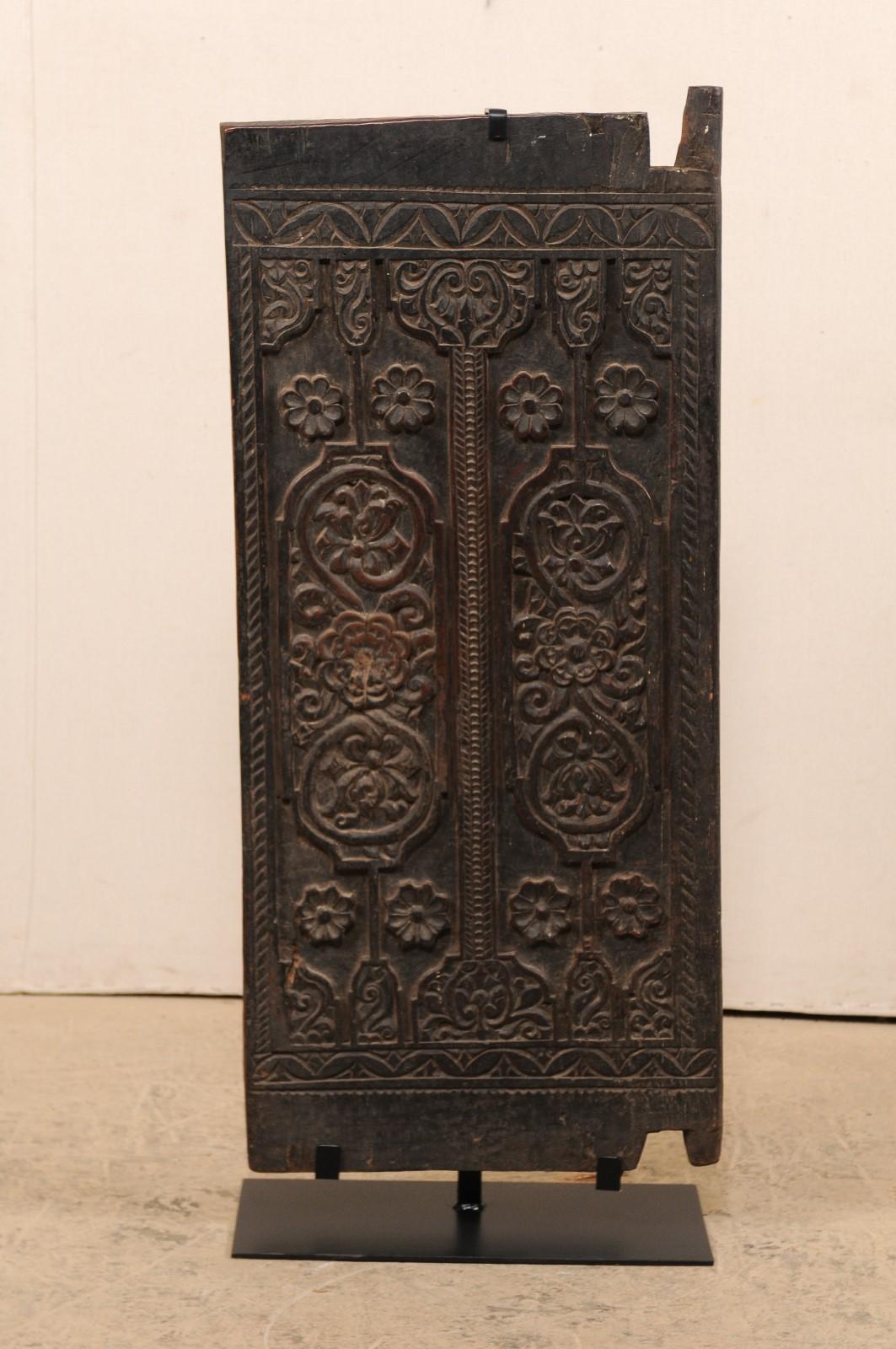 Porte de grange à riz en bois sculpté balinais de petite taille, datant du début ou du milieu du 20e siècle, sur un support en fer personnalisé. Cette porte en bois de Bali est ornée d'accents sculptés à la main dans un motif floral élaboré qui orne