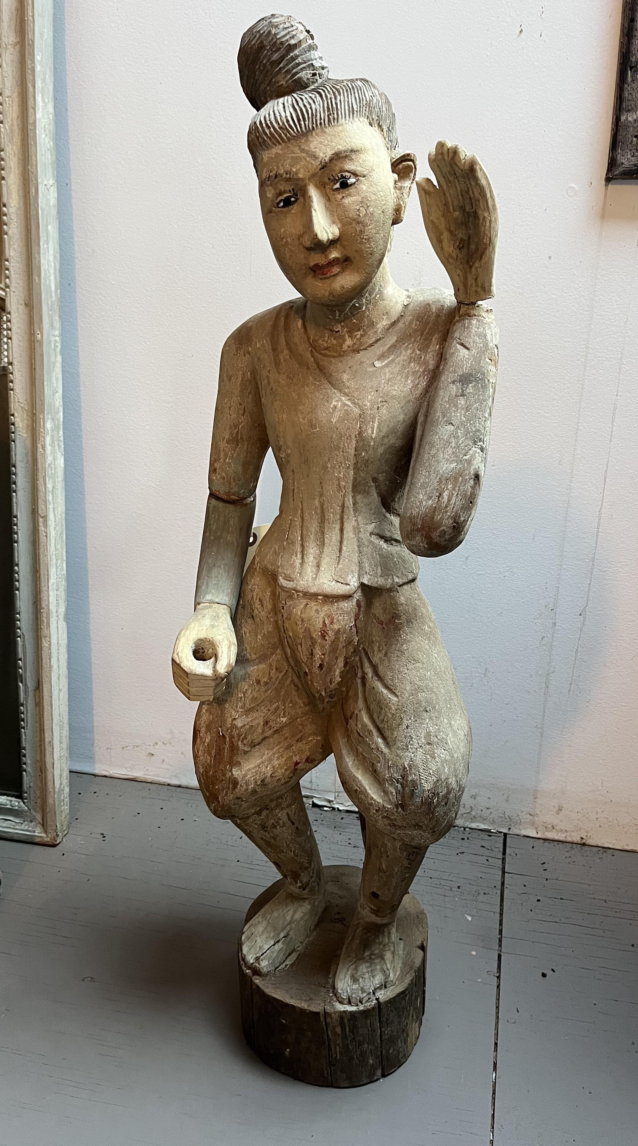 A carved wood statue of a male Balinese dancer in traditional clothing, late 19th century-early 20th century. Retains much of its original painted finish.
