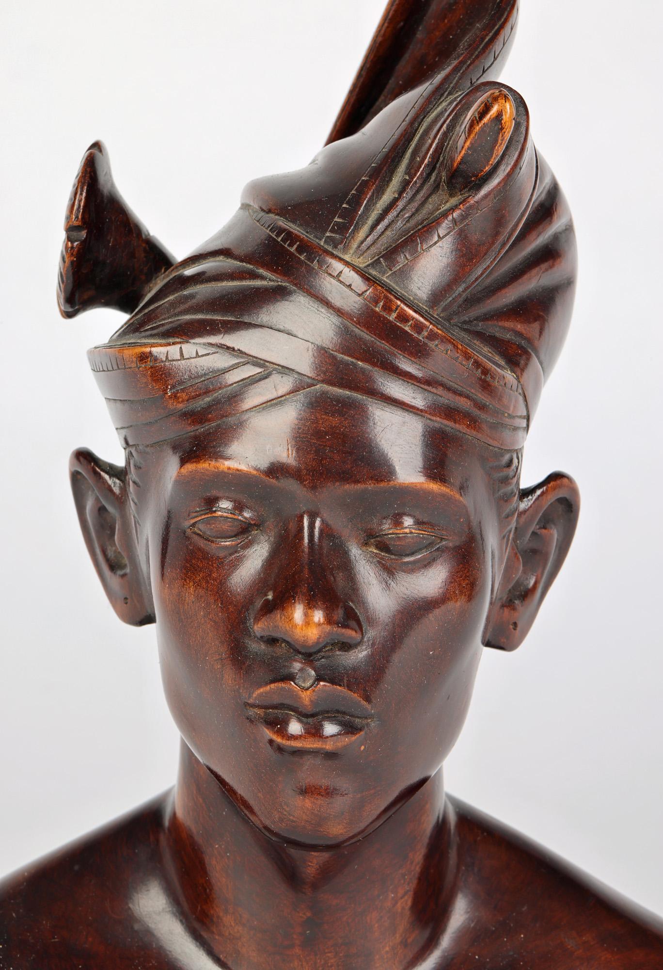 A well carved wooden portrait bust of a young man carved by a Balinese artist around the mid 20th century. The bust is carved from a single piece if wood and is well carved with good detail portraying the young man wearing a traditional headdress.