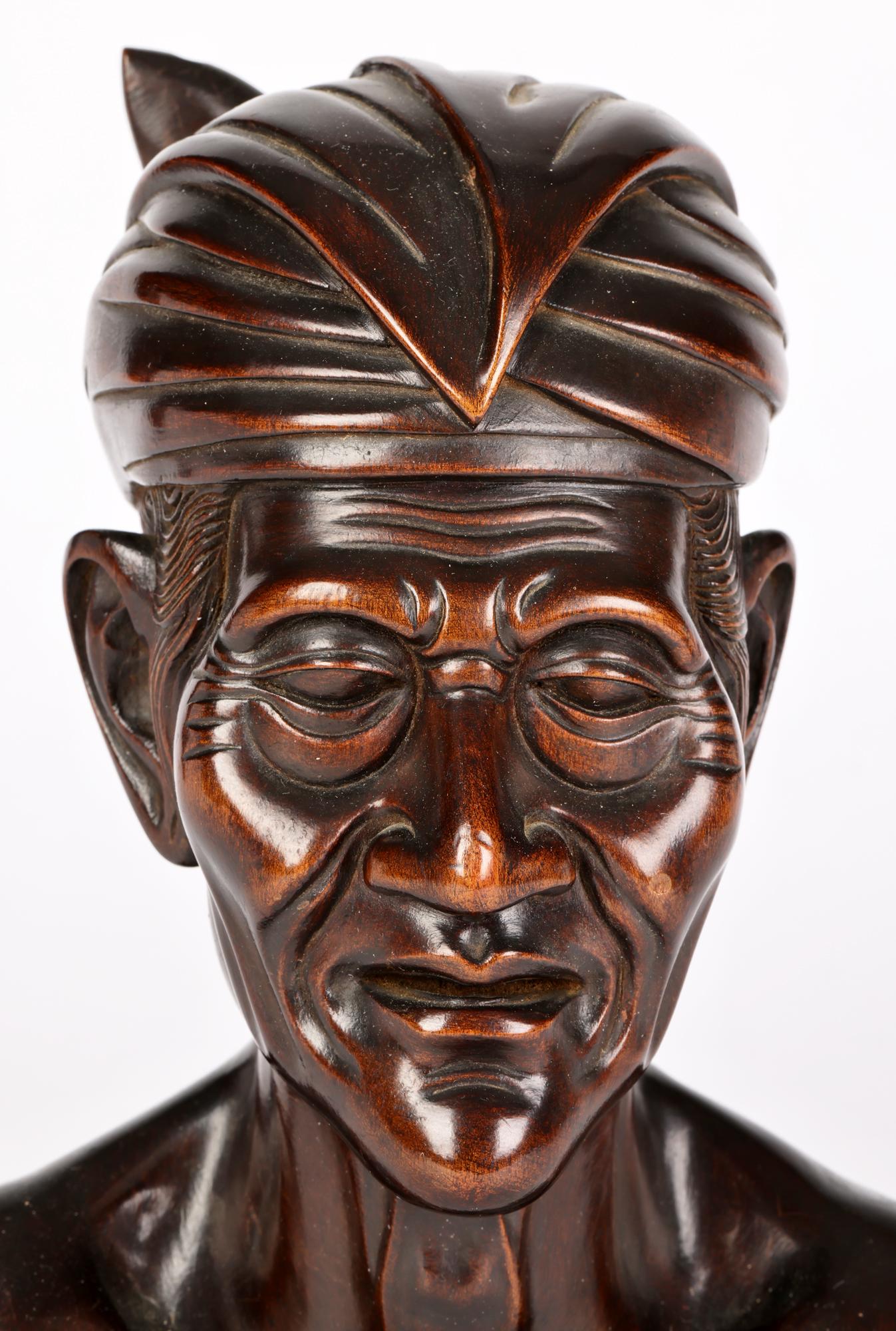 A well carved wooden portrait bust of an elderly man carved by a Balinese artist around the mid 20th century. The bust is carved from a single piece if wood and is well carved with good detail portraying the man wearing a traditional headdress.