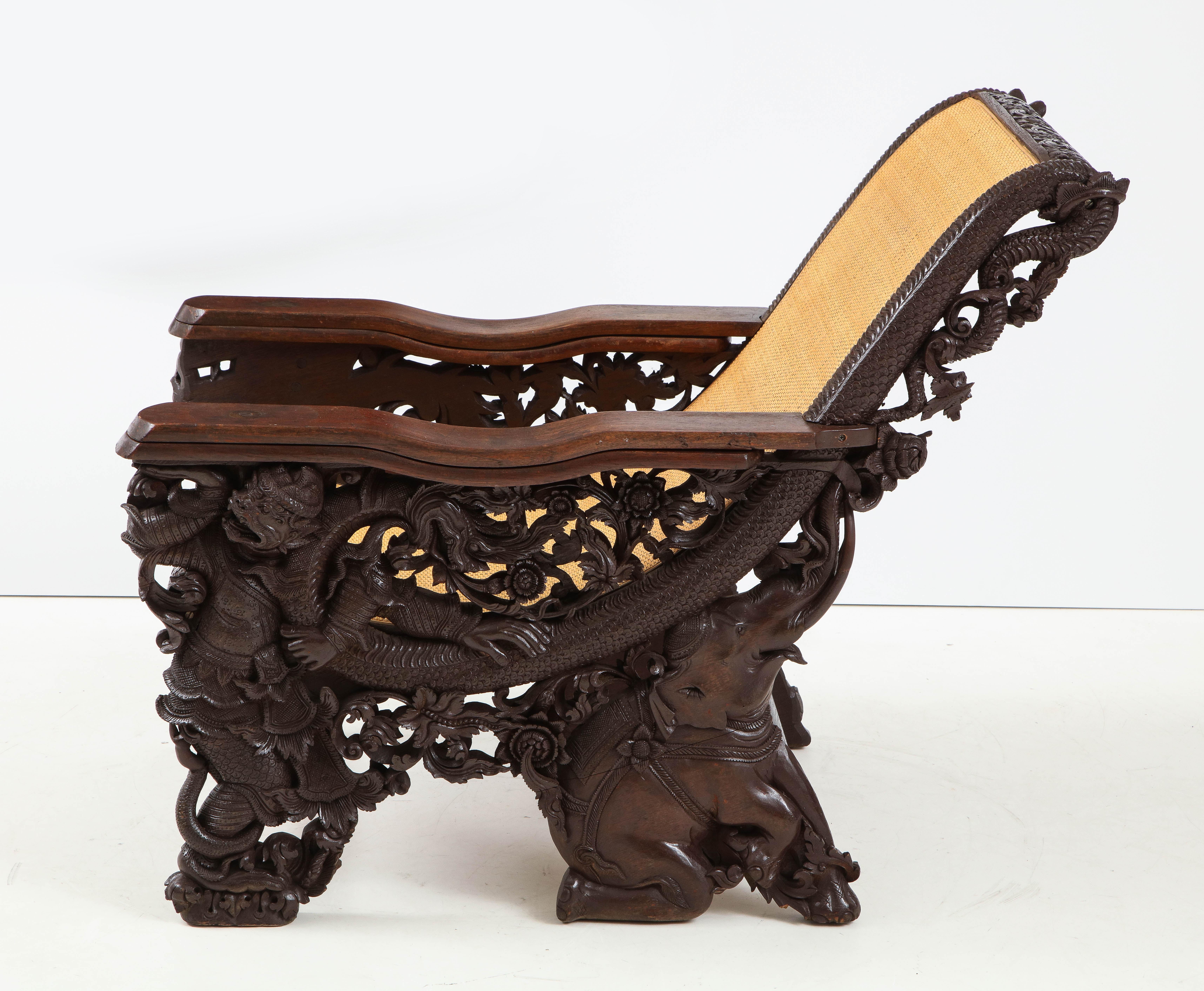 Exquisite hand carved plantation chair featuring elephants, foliage, flowers and snake motifs. A new tightly woven grass cloth seat and back complete this masterful work of art chair.